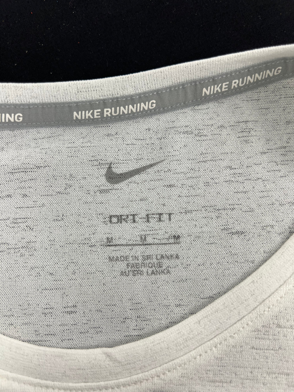 Close-up of inner neckline of Nike running t-shirt showing Dri-FIT label and size medium