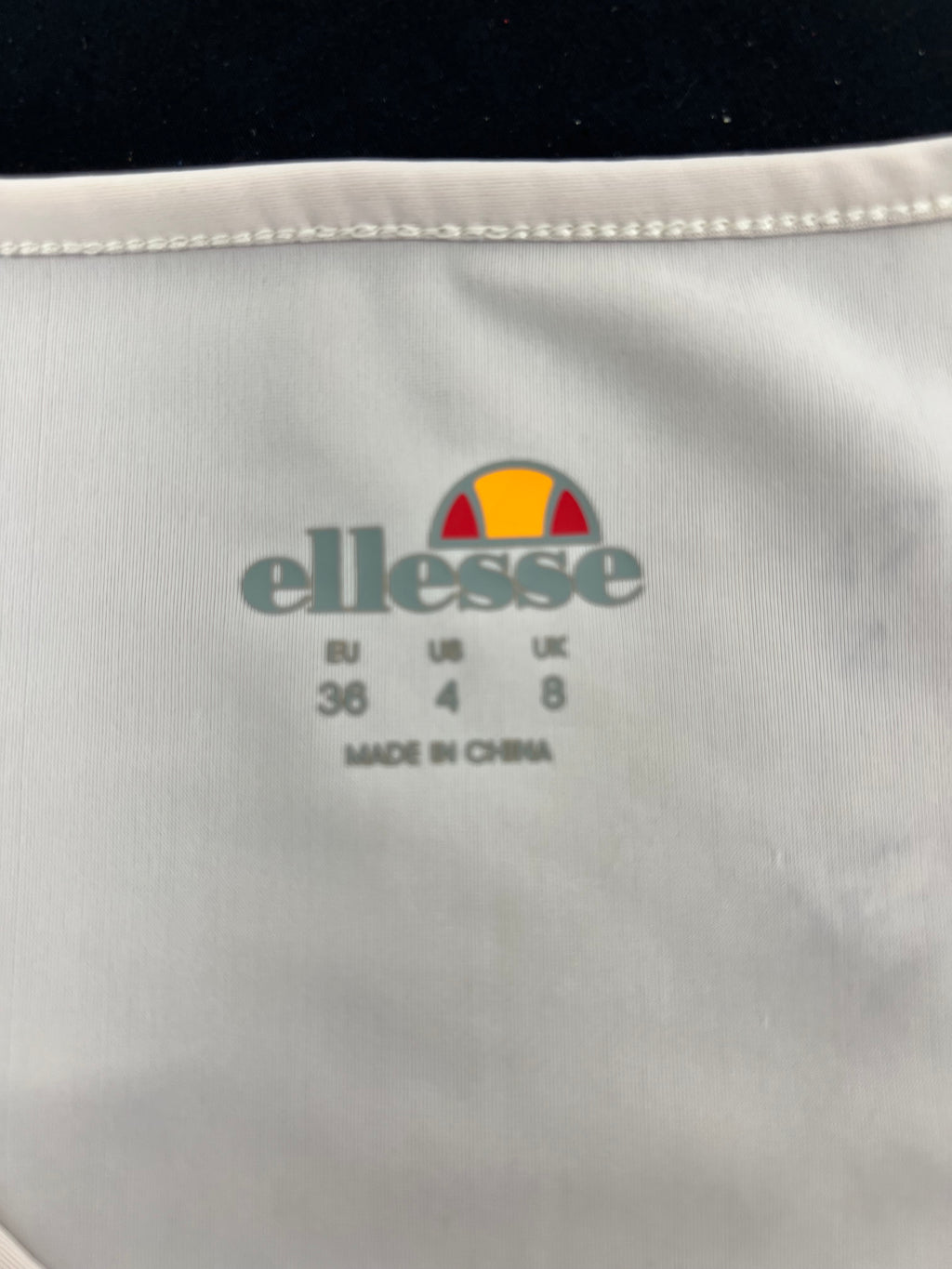 Close-up of Ellesse brand label printed inside the t-shirt showing size EU 36 US 4 UK 8 made in China