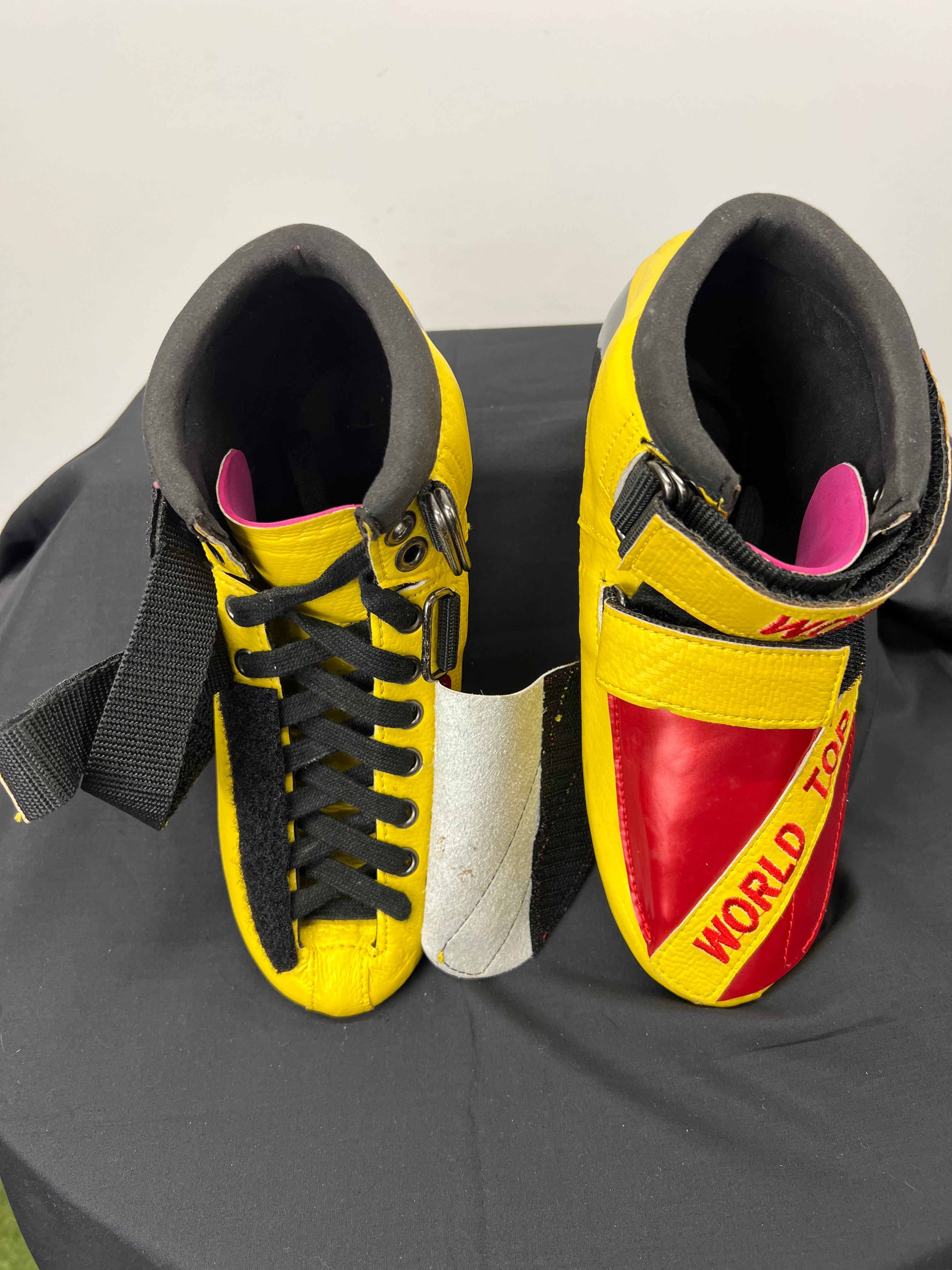 Top view of pair of World Top short track skates with open lace fastening and red embroidered yellow straps