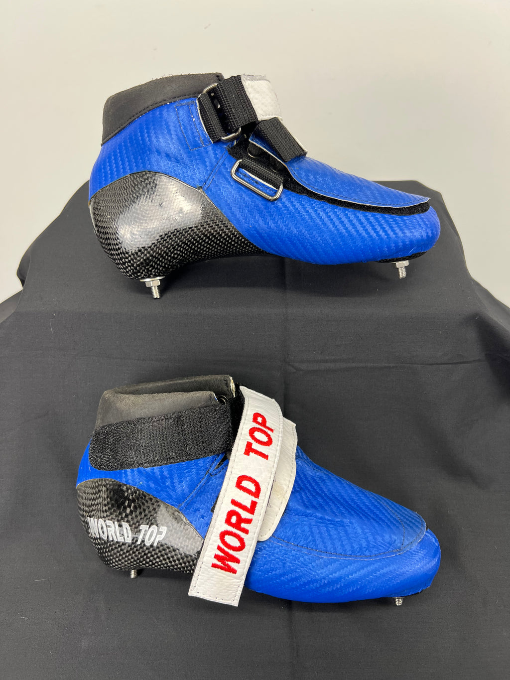 Side view of blue World Top short track skate boot with black carbon fibre heel and ankle strap