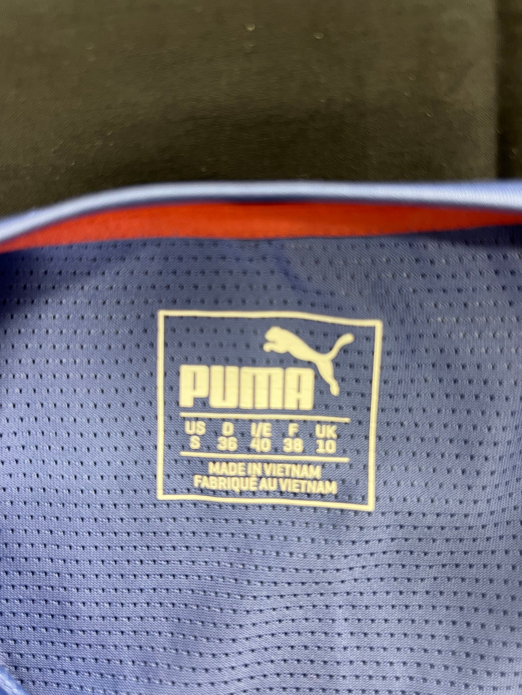 Close-up of Puma size label inside the purple patterned T-shirt showing size 10 UK
