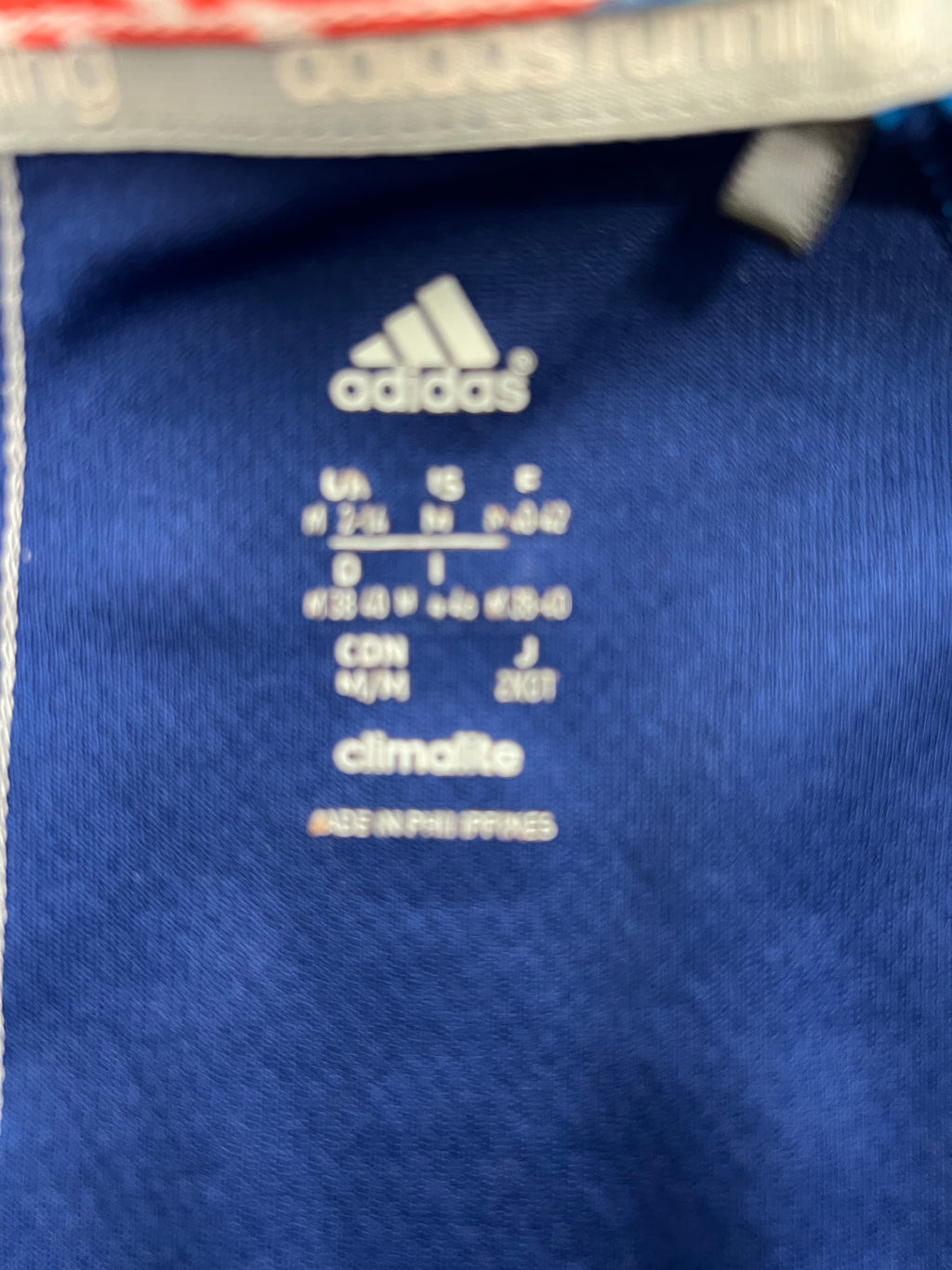 Close-up of Adidas climate technology label and size medium info printed on navy blue fabric