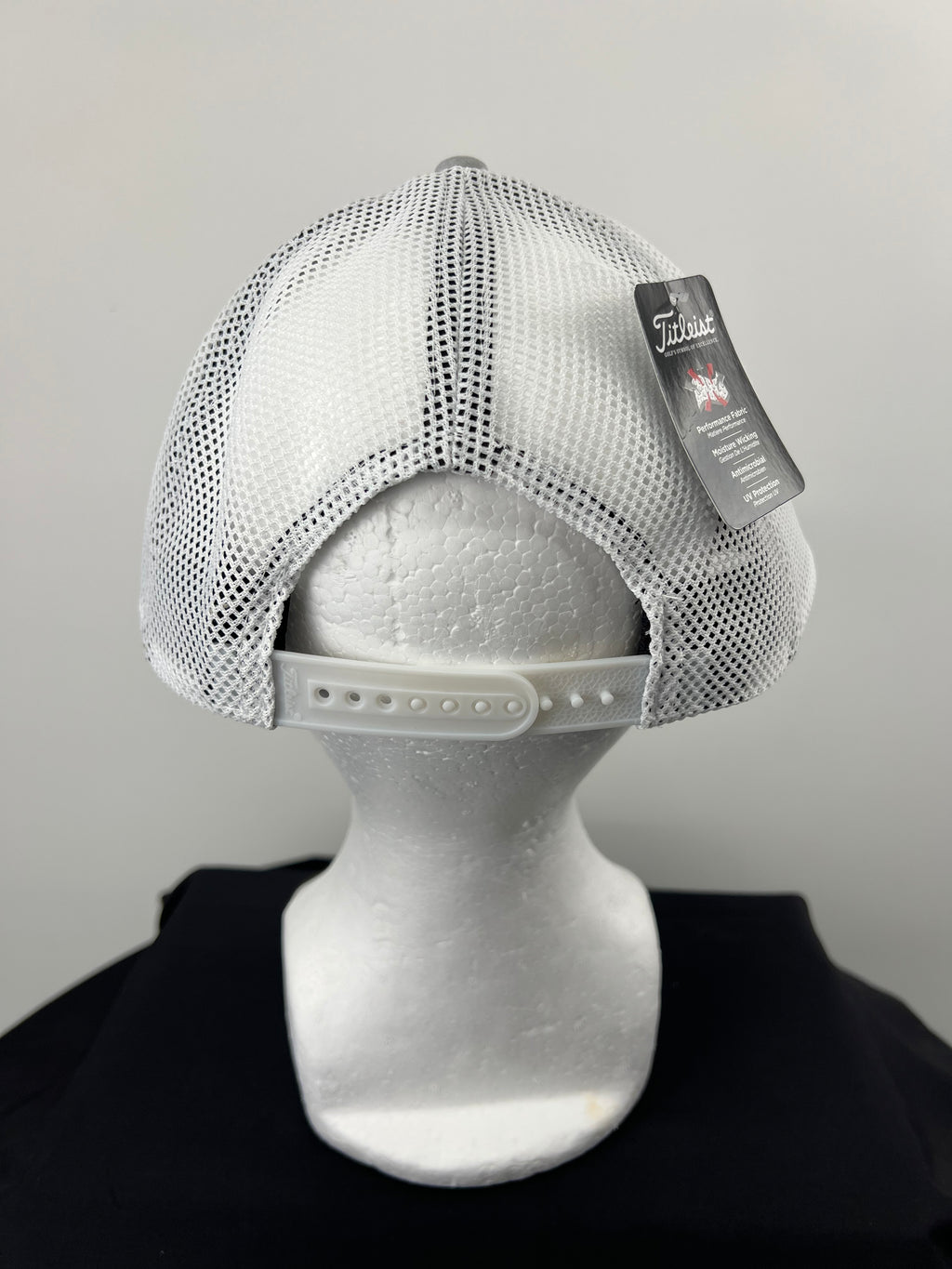 Rear view of white mesh back of Titleist cap with adjustable snapback closure