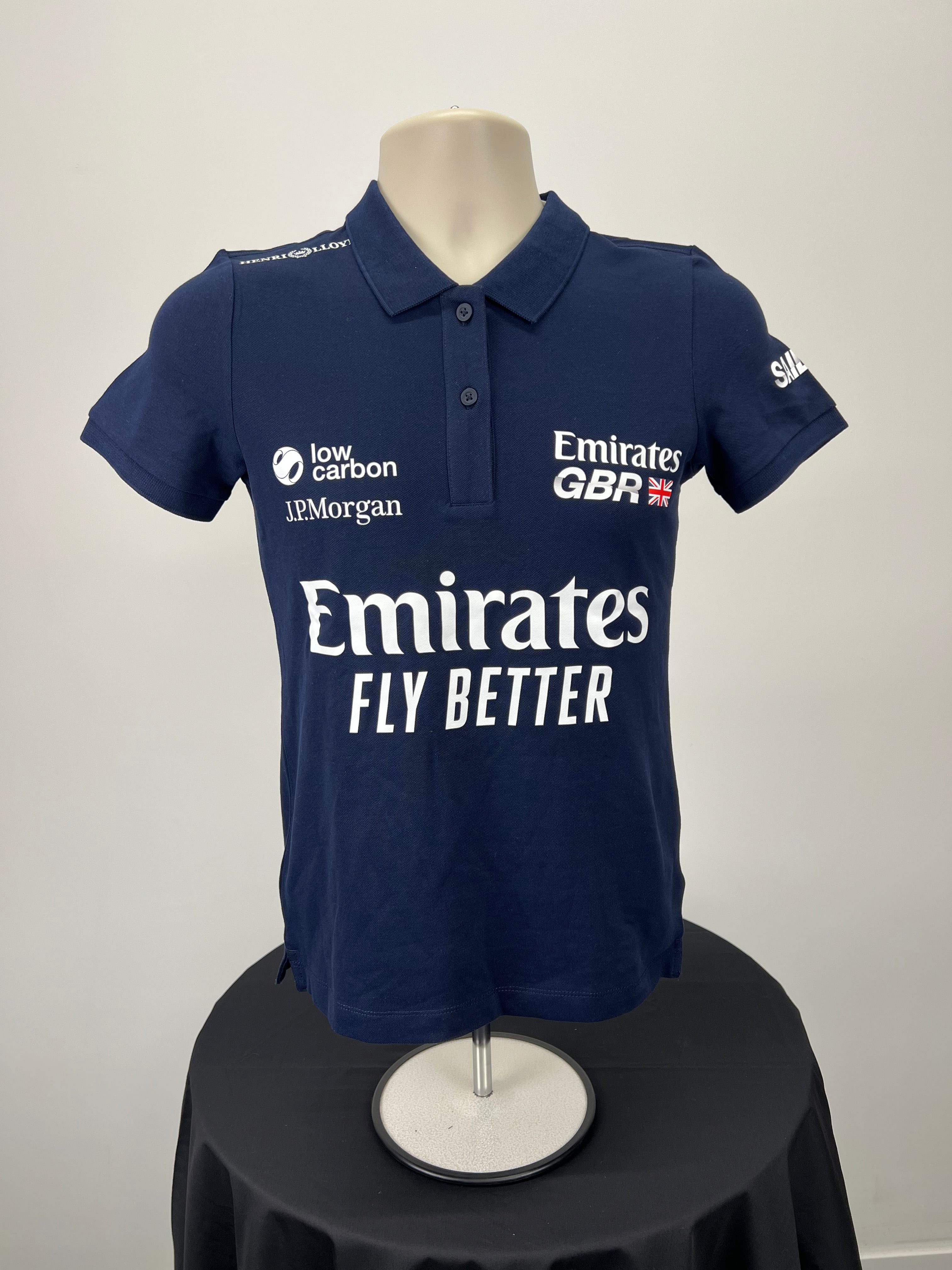 Front view of women's navy blue Emirates GBR x Henri Lloyd polo shirt with multiple logos
