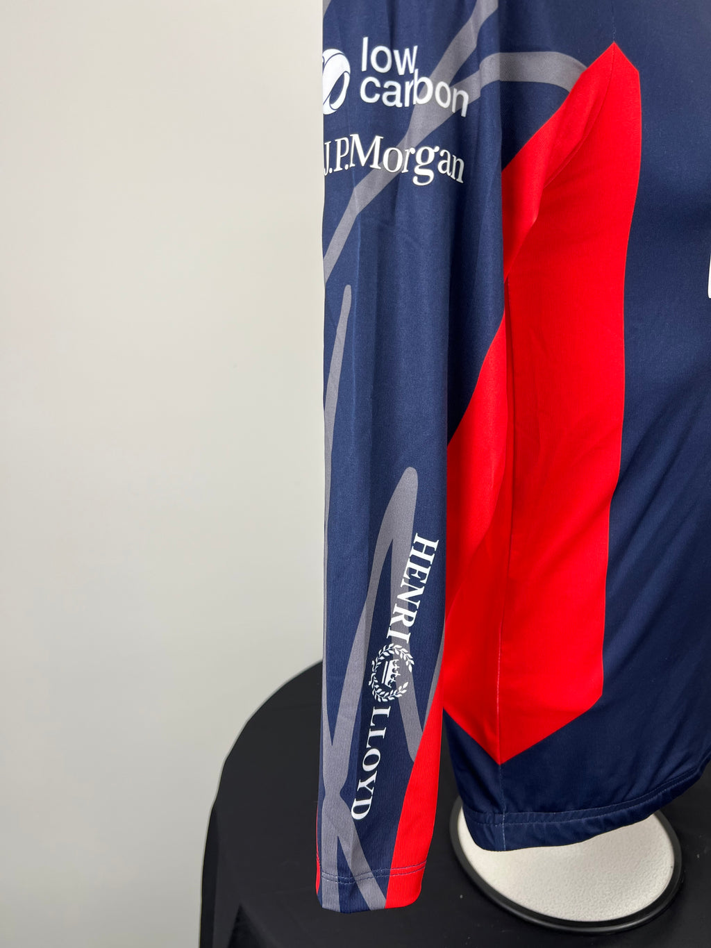 Close-up of right sleeve showing low carbon and J.P. Morgan sponsor logos on navy and red rash vest