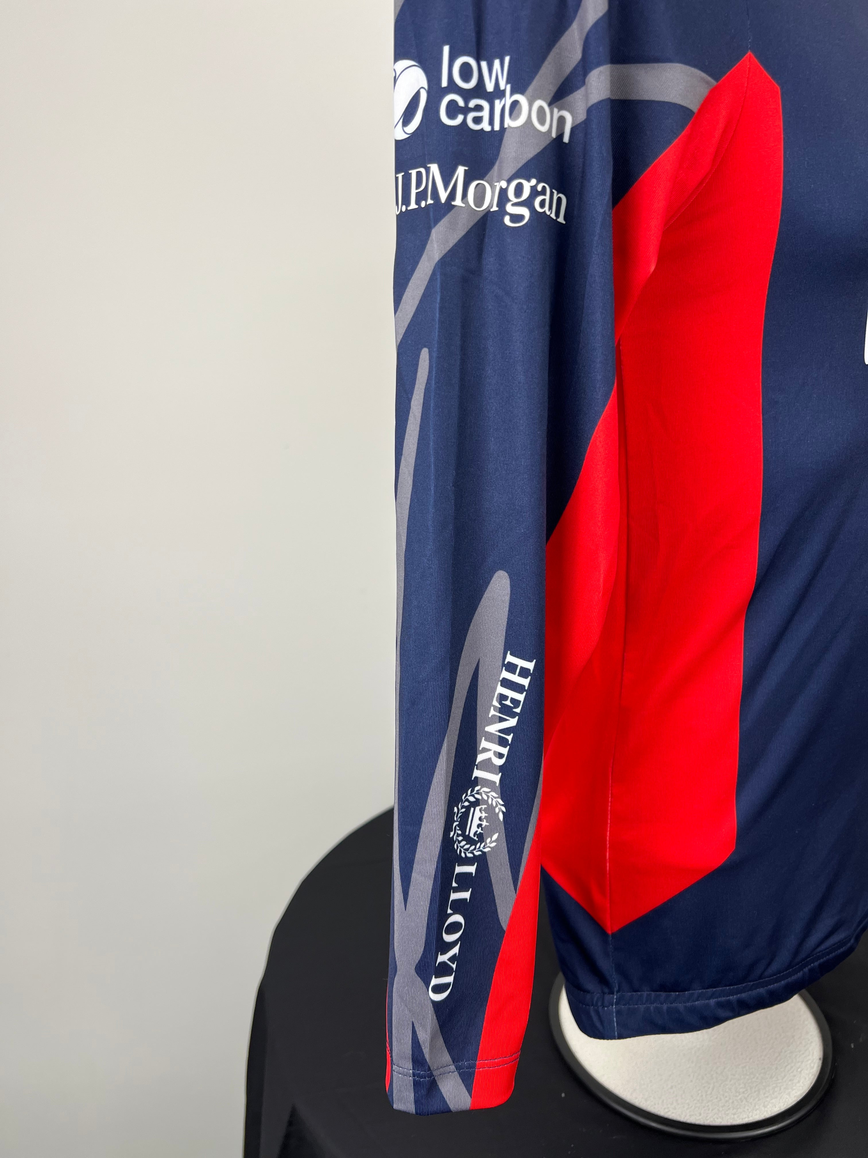Close-up of right sleeve showing low carbon and J.P. Morgan sponsor logos on navy and red rash vest