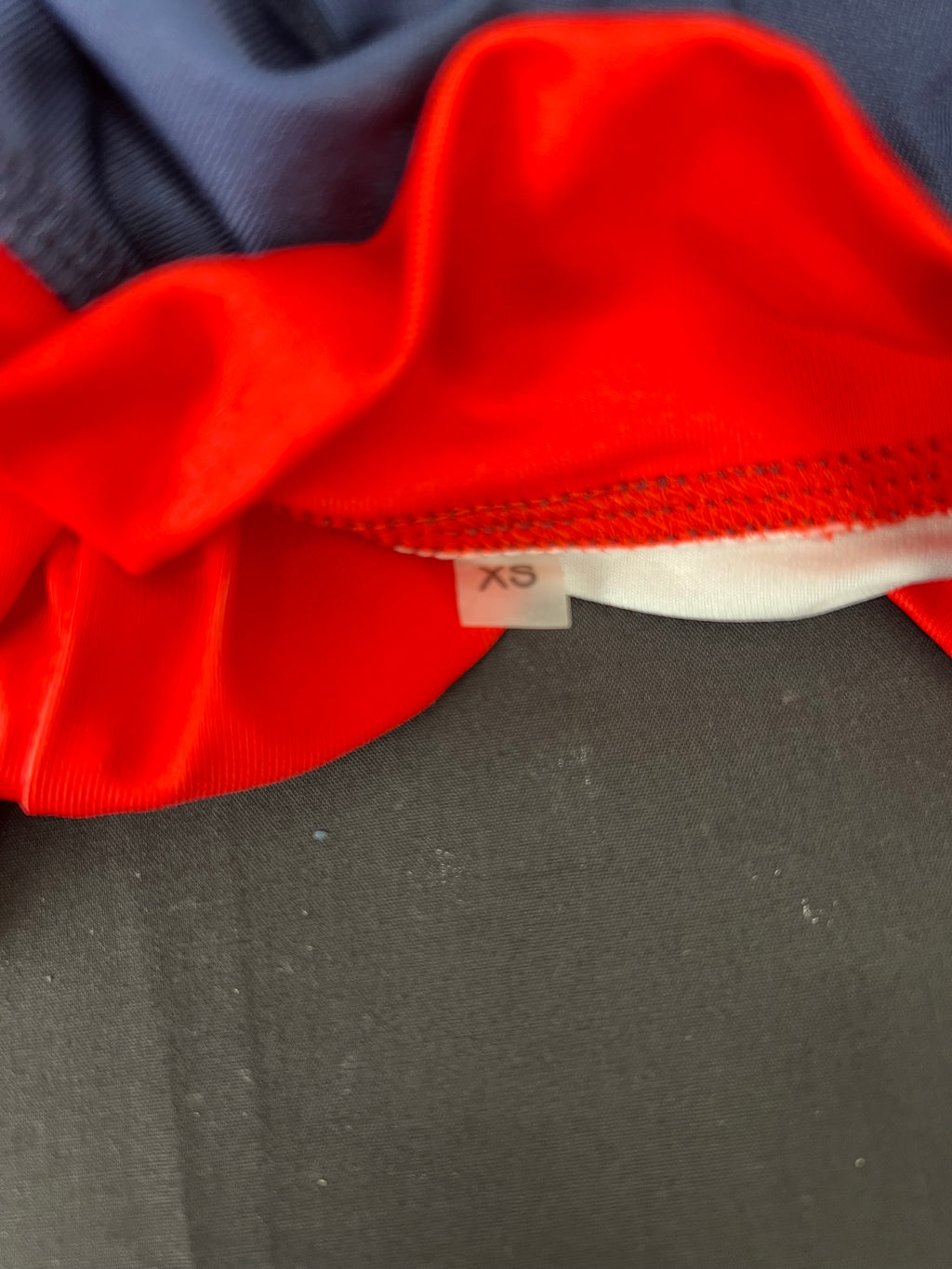 Close-up showing the high collar in red and XS size label inside Emirates Team GBR rash vest