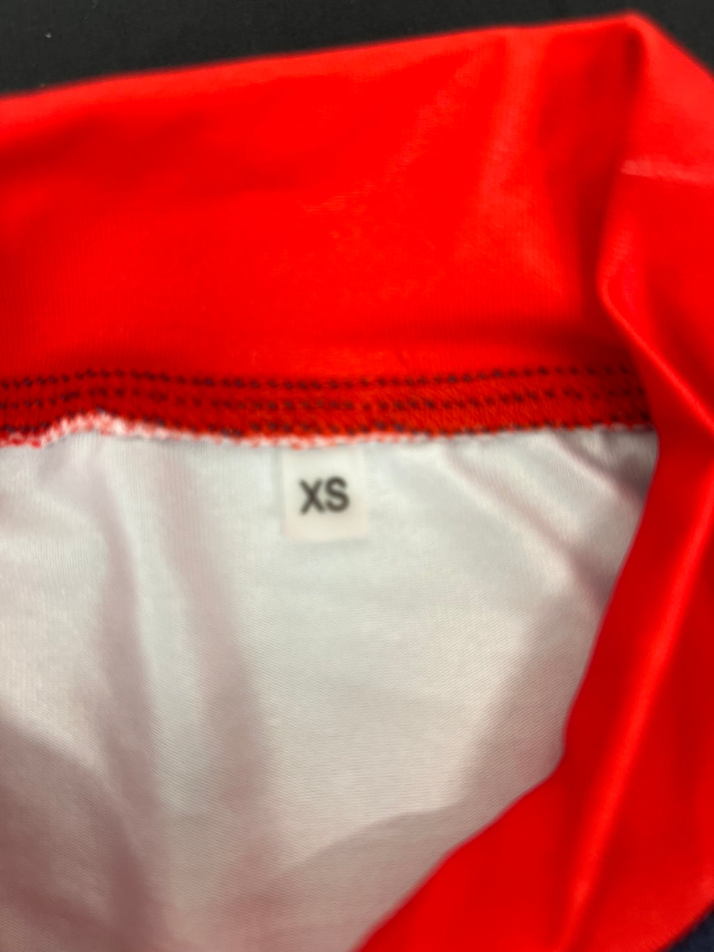 Inside label showing size XS on red and navy Emirates Team GBR rash vest