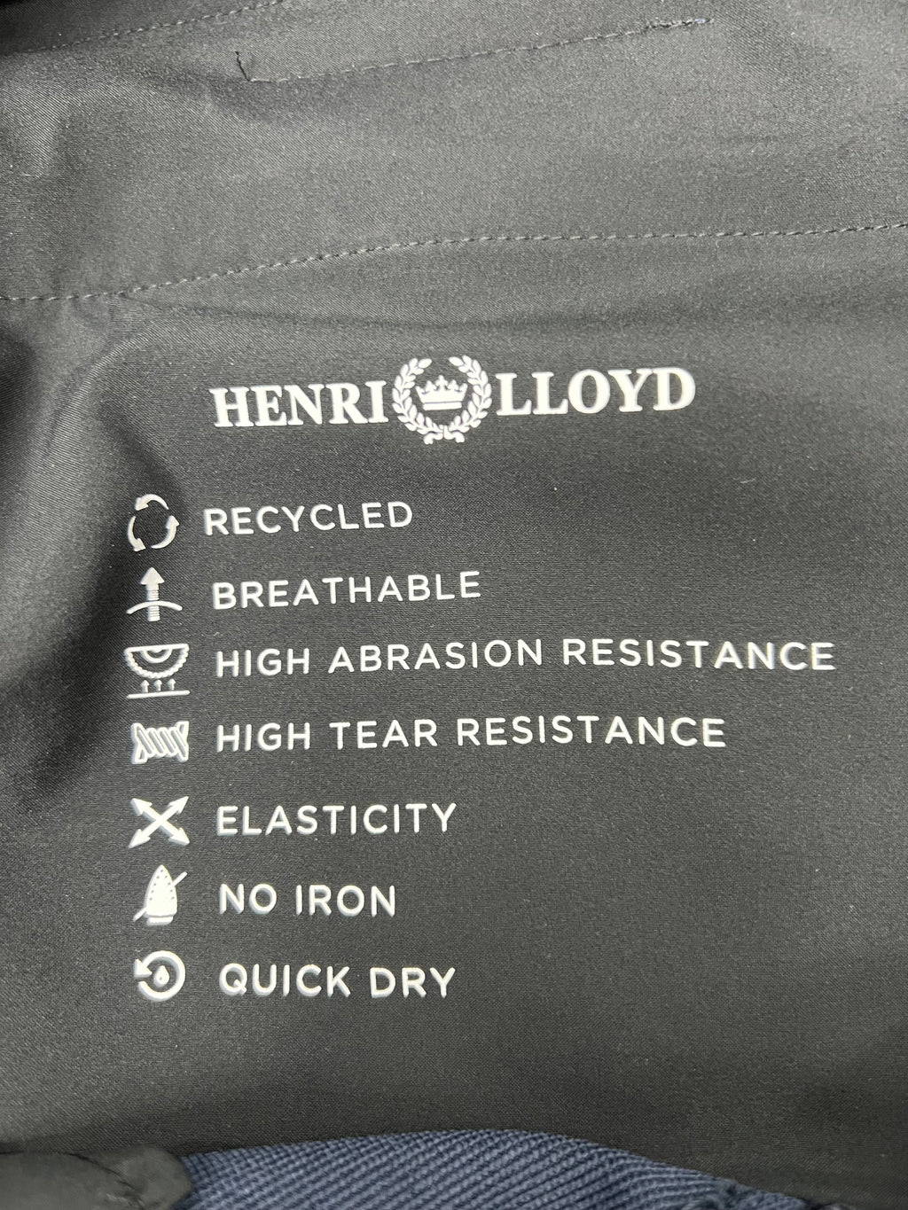 Close-up detail of Henri Lloyd fabric features label mentioning recycled material, breathability, and quick dry