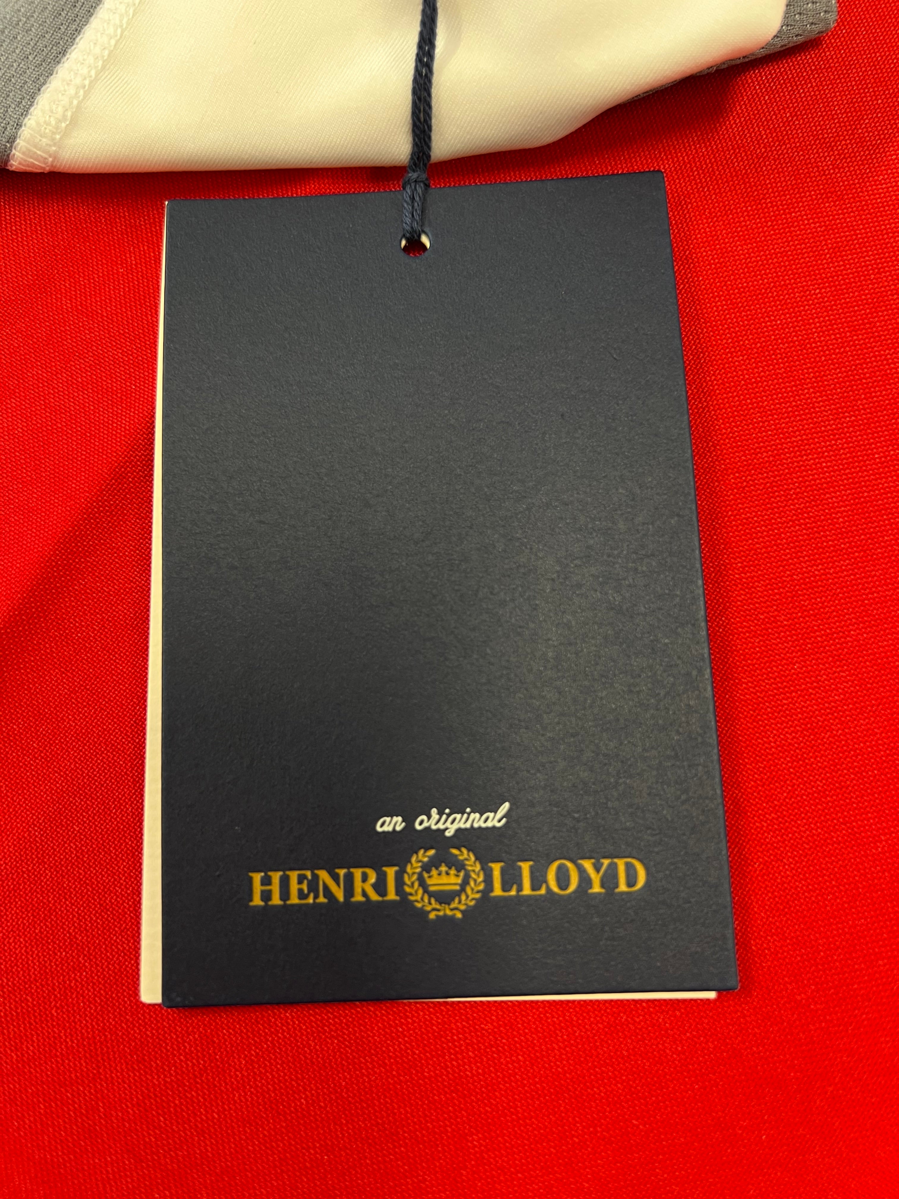 Close-up of Henri Lloyd branded black and gold hang tag against red background