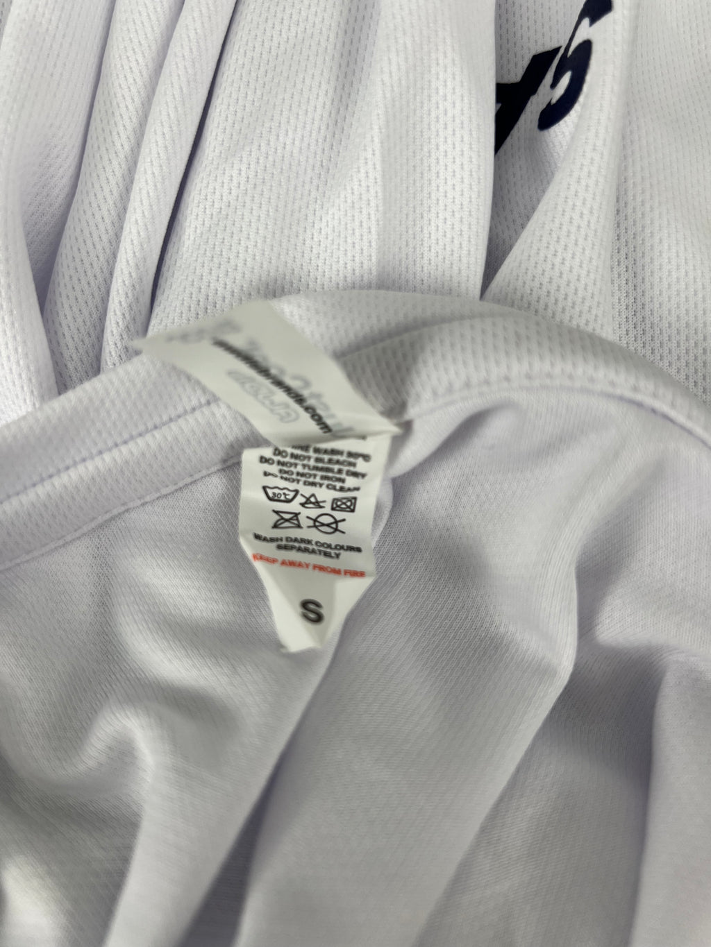 Close-up of care label inside the Women’s Emirates Team GBR x Henri Lloyd 2025 white long sleeve tee indicating size small and washing instructions