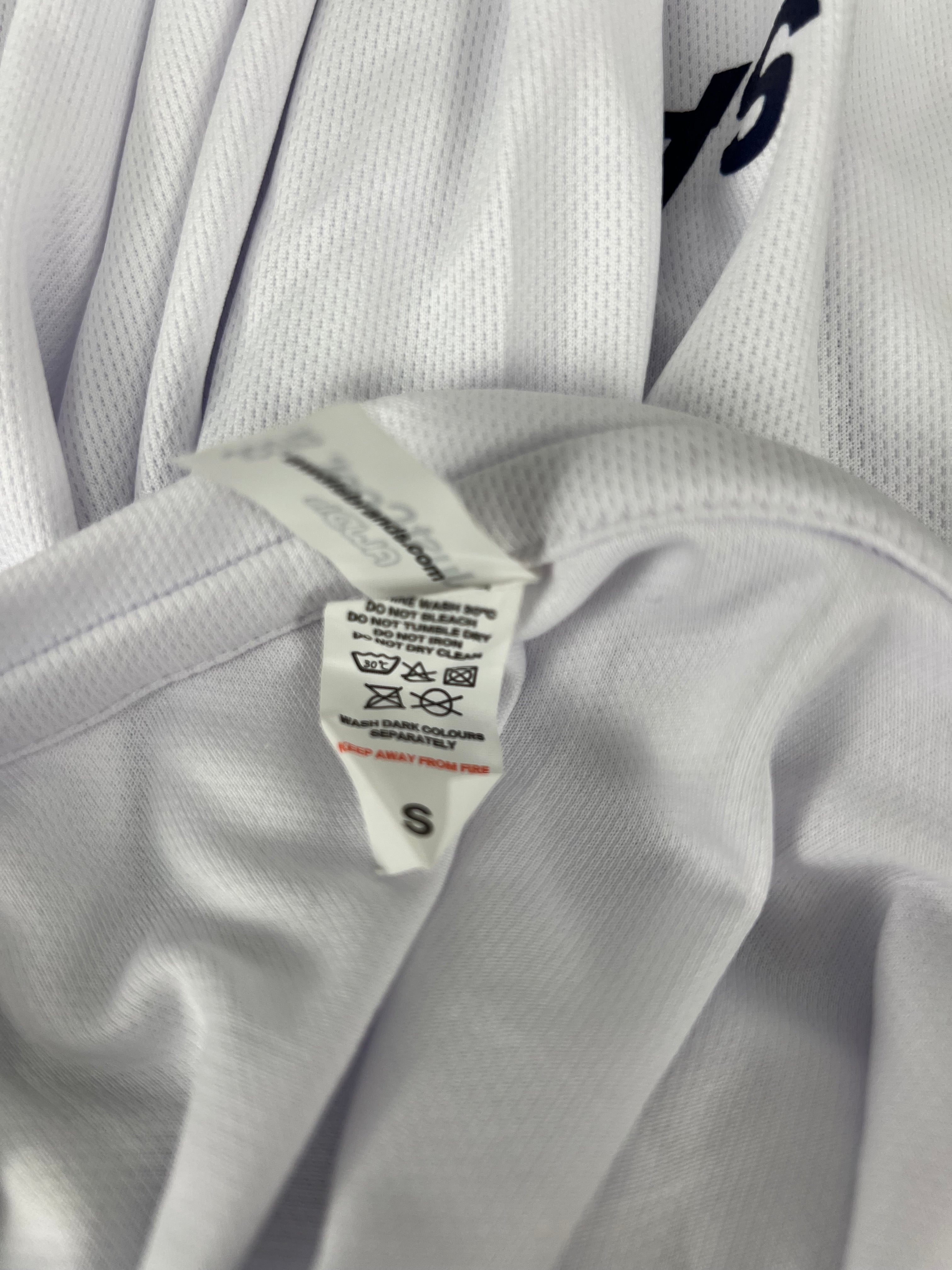 Close-up of care label inside the Women’s Emirates Team GBR x Henri Lloyd 2025 white long sleeve tee indicating size small and washing instructions