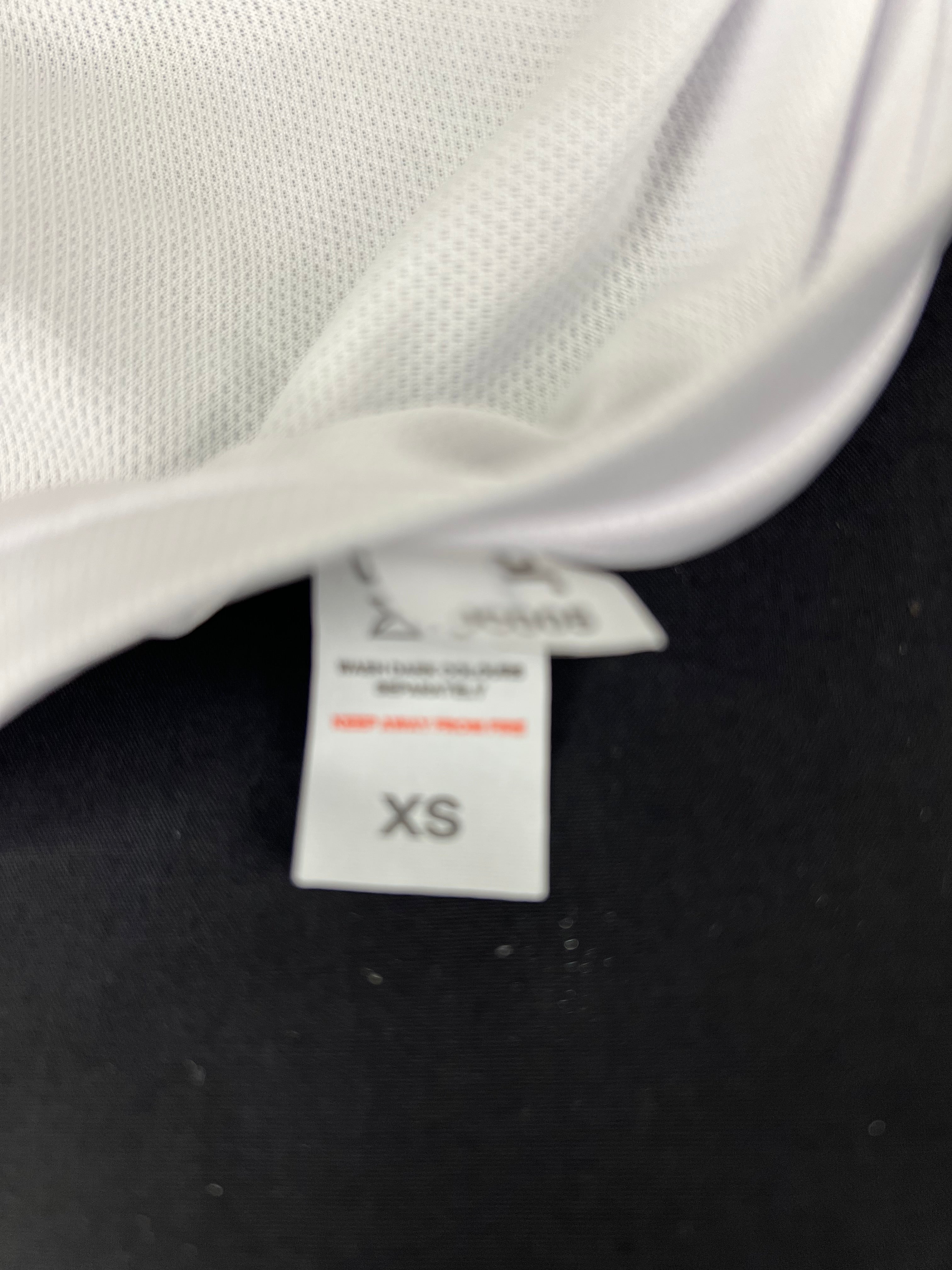 Close-up of size XS tag on the inside hem of the white technical fabric top