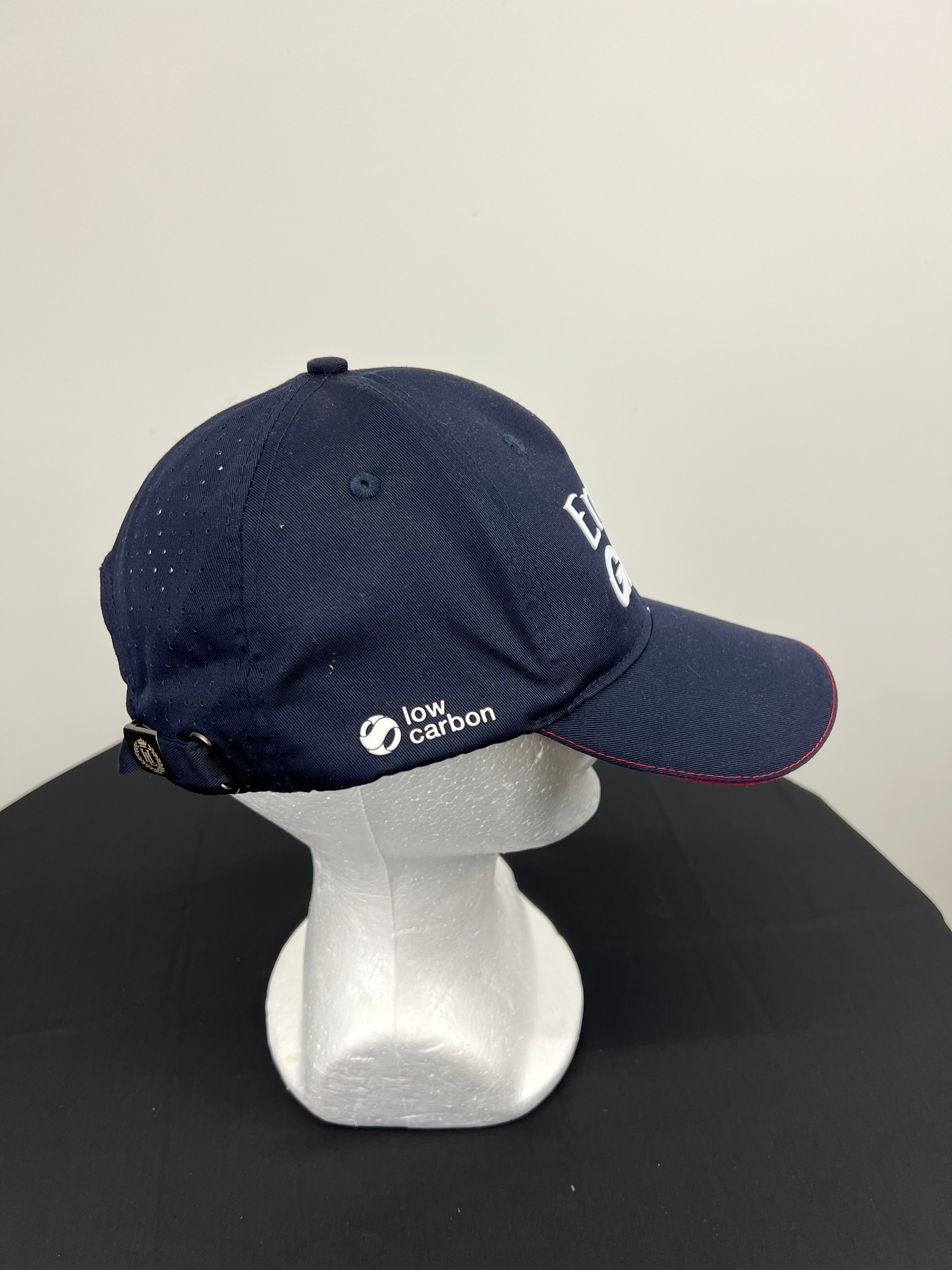 Side view of navy blue cap showing breathable perforations and low carbon logo