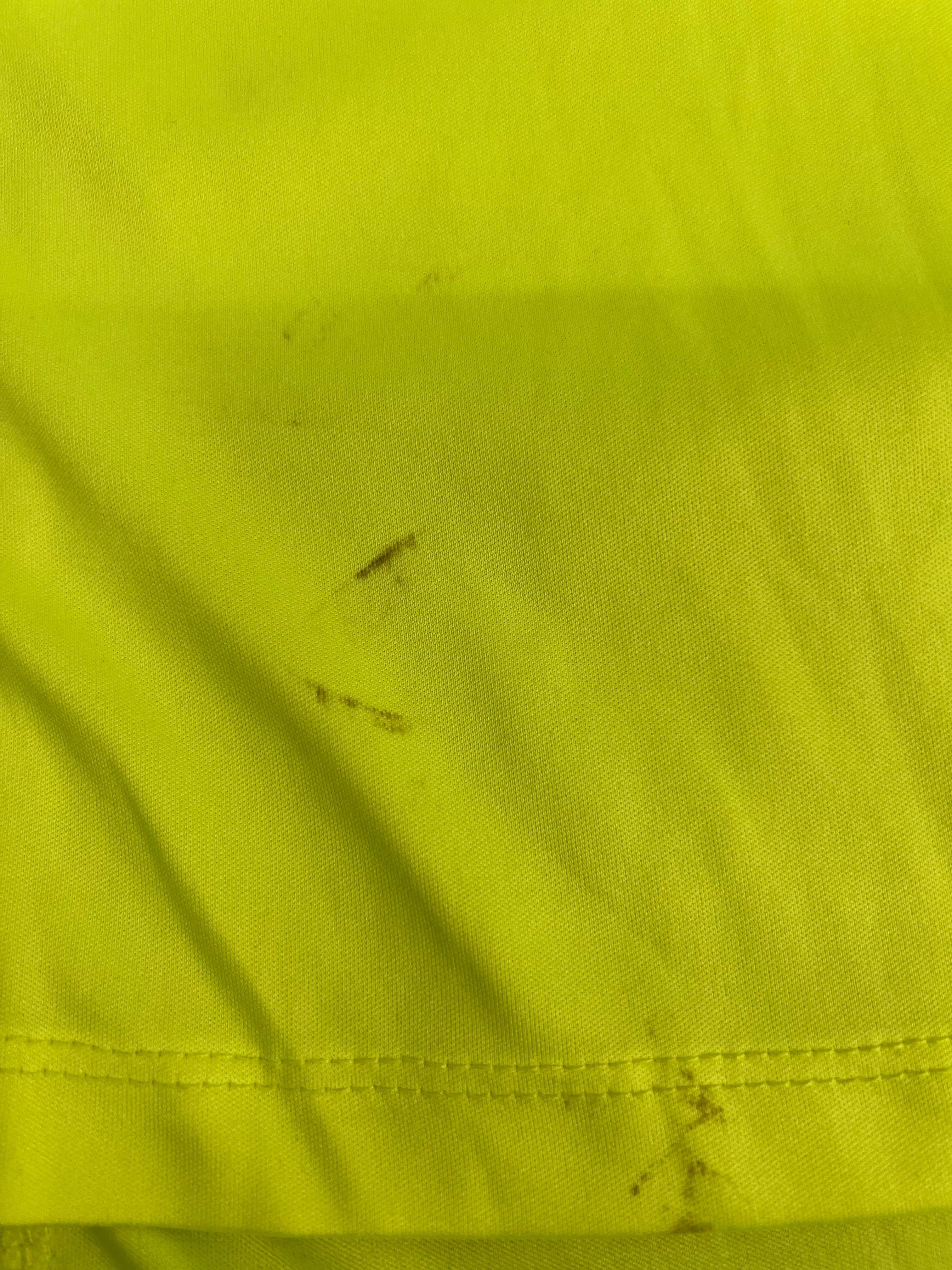 Close-up of minor dirt marks on bright green running top near hem