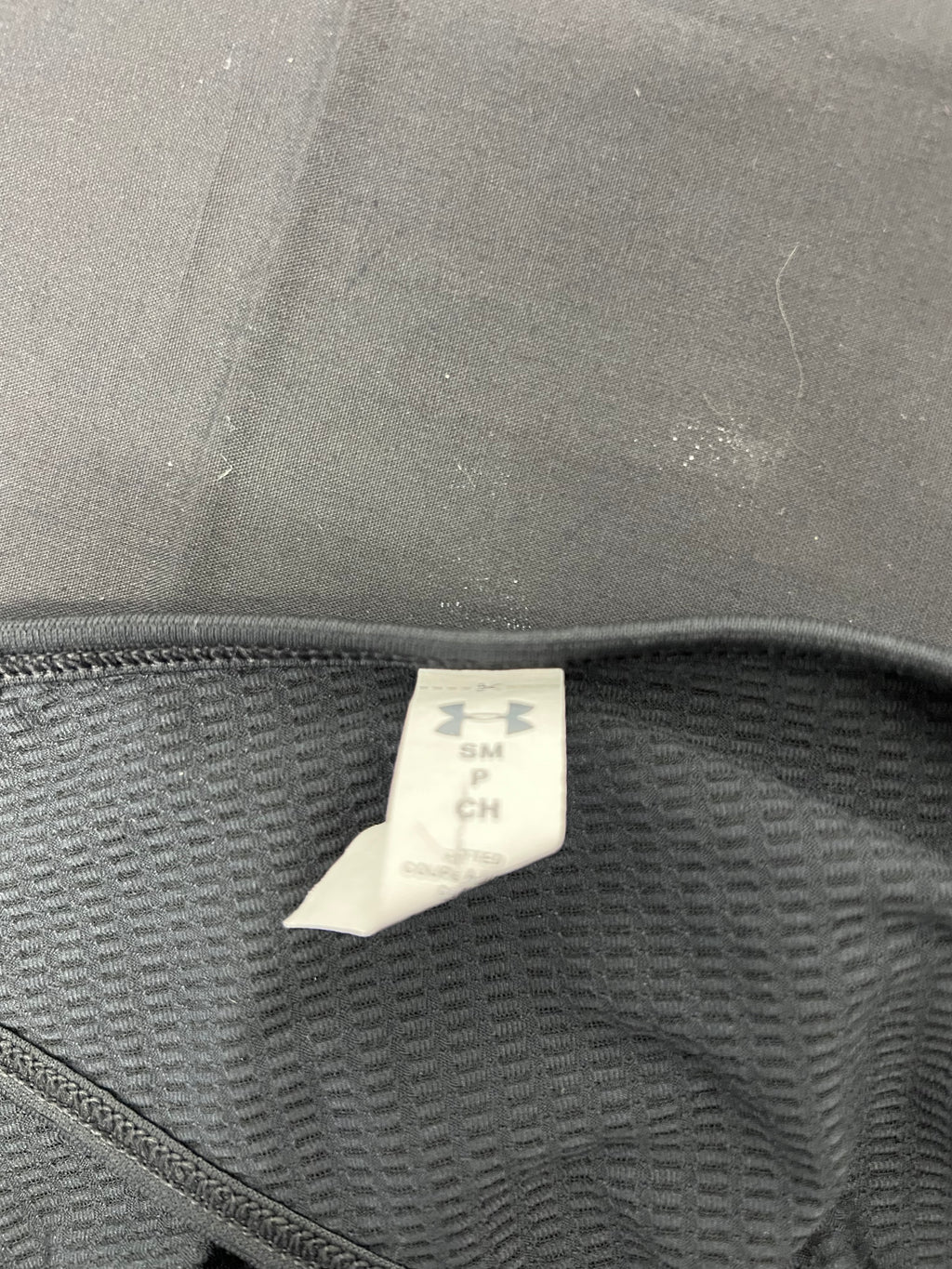 Close-up of size tag inside under armour women's black T-shirt showing size small