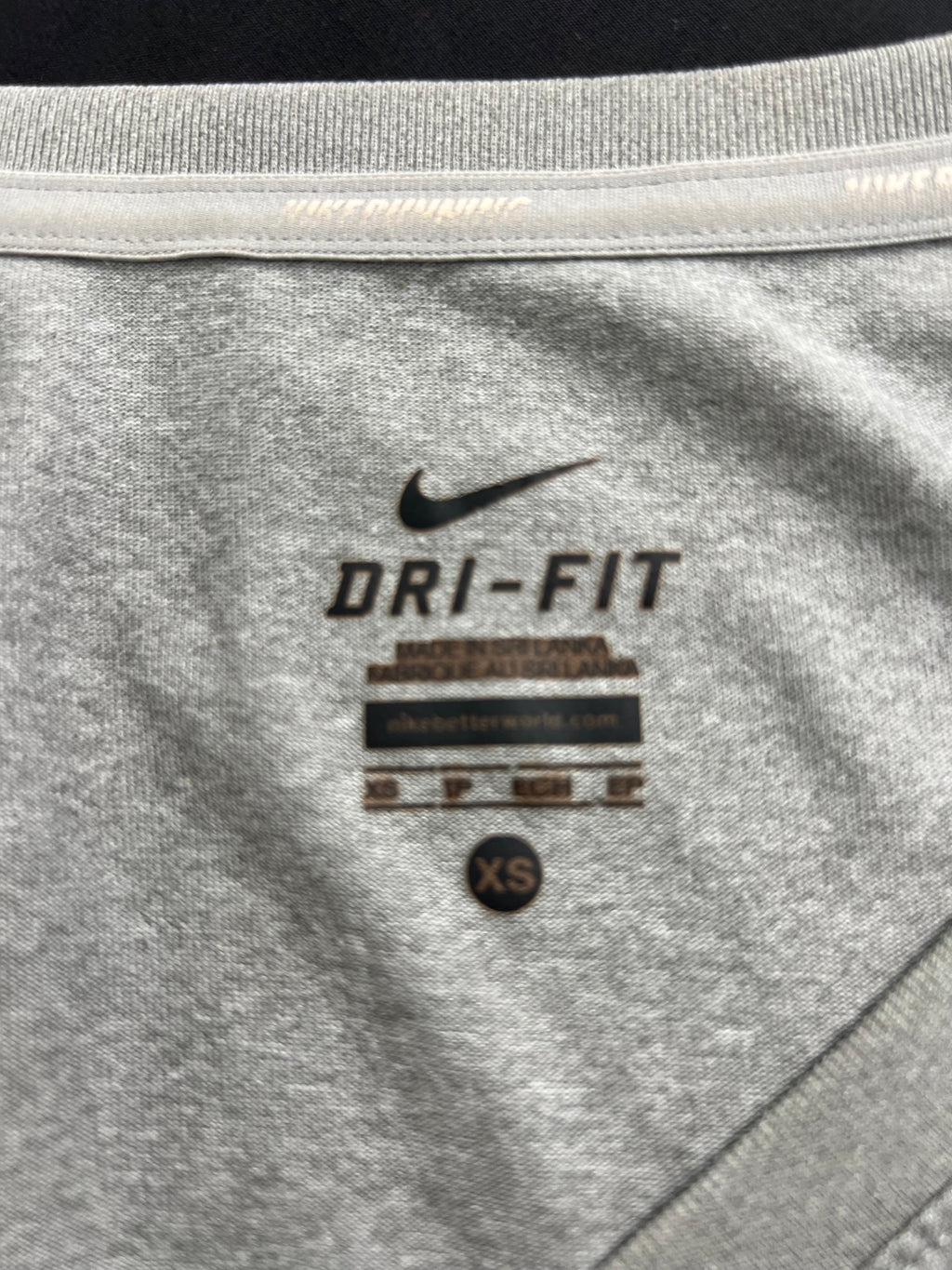 Close-up of inside neck label showing Nike Dri-Fit material and XS size