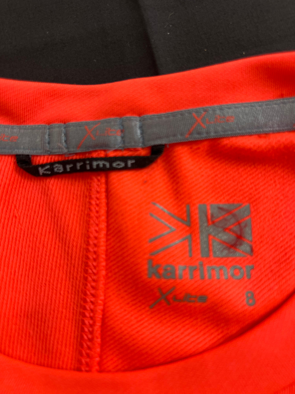 Close-up of Karrimor Xlite logo and inner neck label on red base layer top