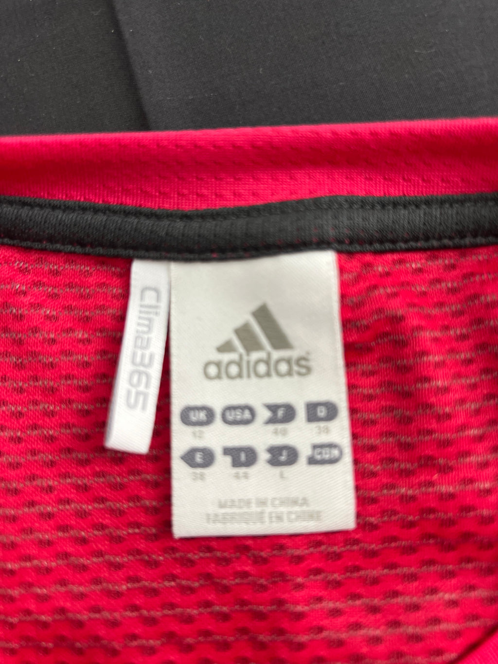 Close-up of Adidas size and care label inside the pink long sleeve base layer top