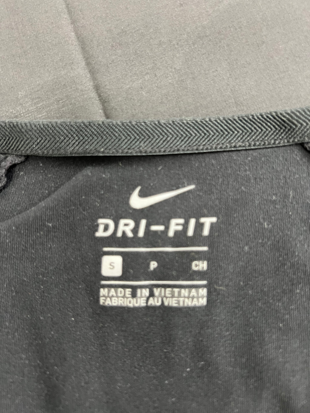 Close-up of Nike Dri-FIT label inside the black V-neck long sleeve top