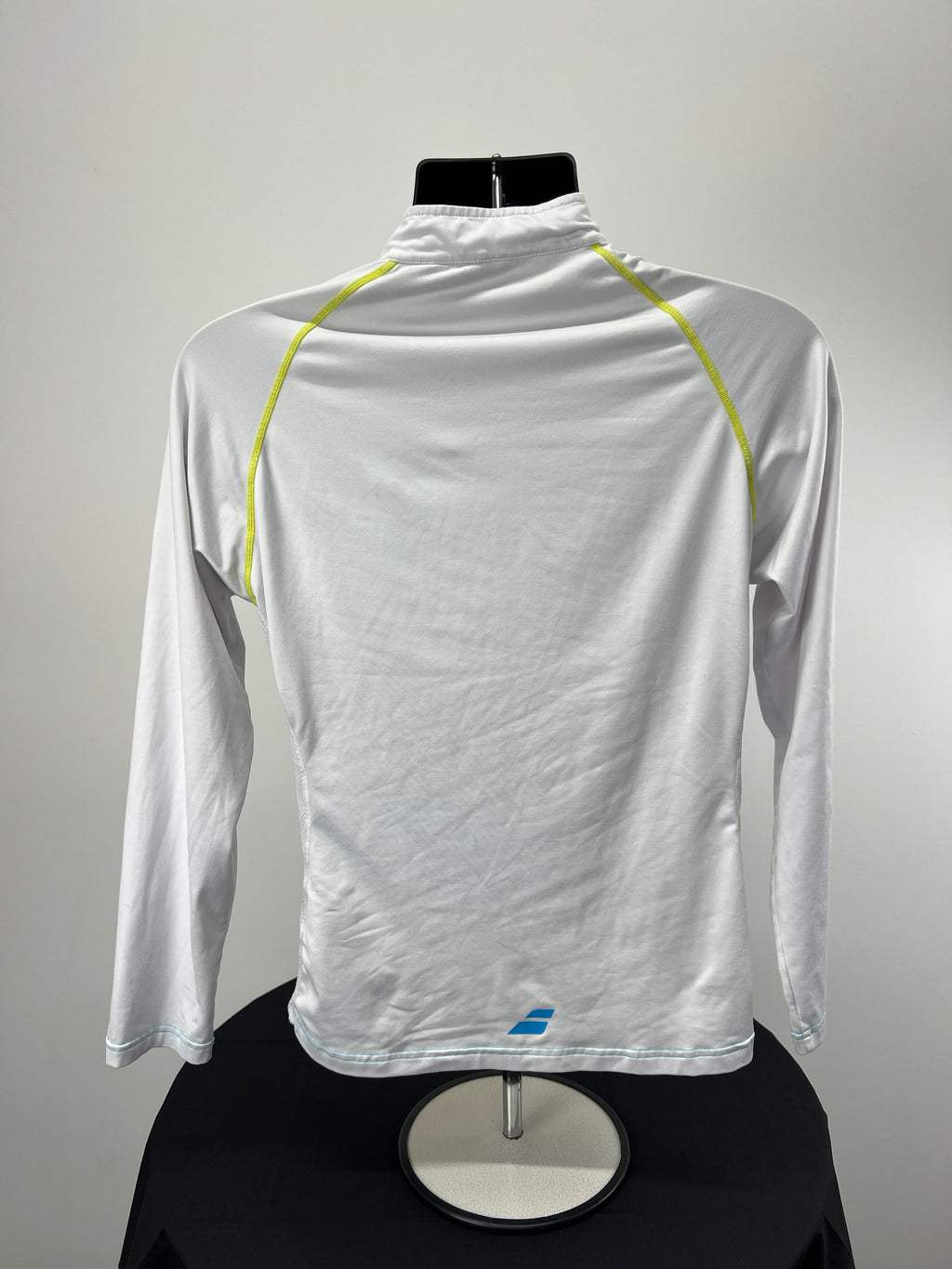 Back view of Babolat white long sleeve tennis top showing neon yellow raglan seams and bottom logo
