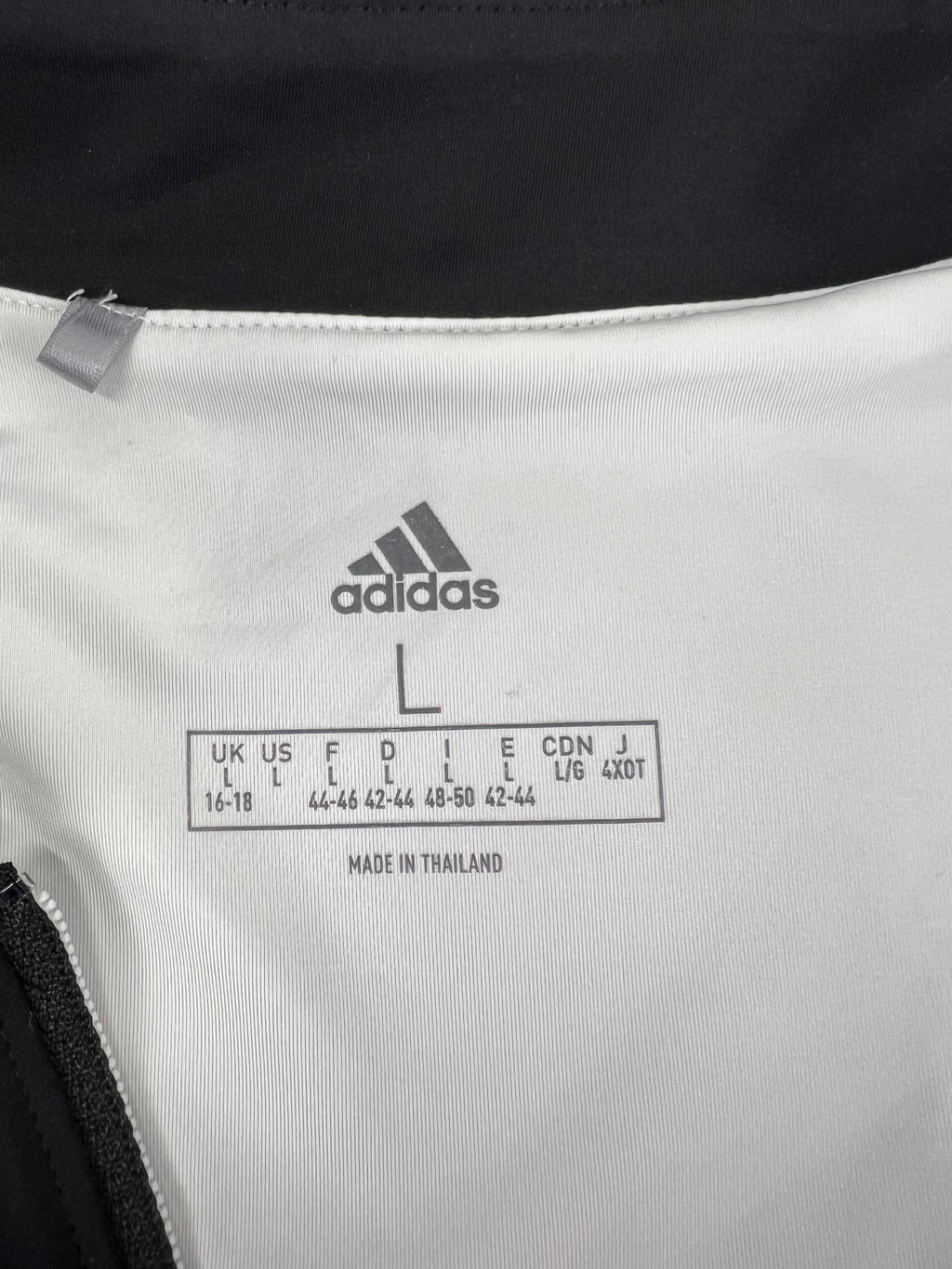 Close-up of Adidas sizing label inside black sleeveless top with size UK 16-18