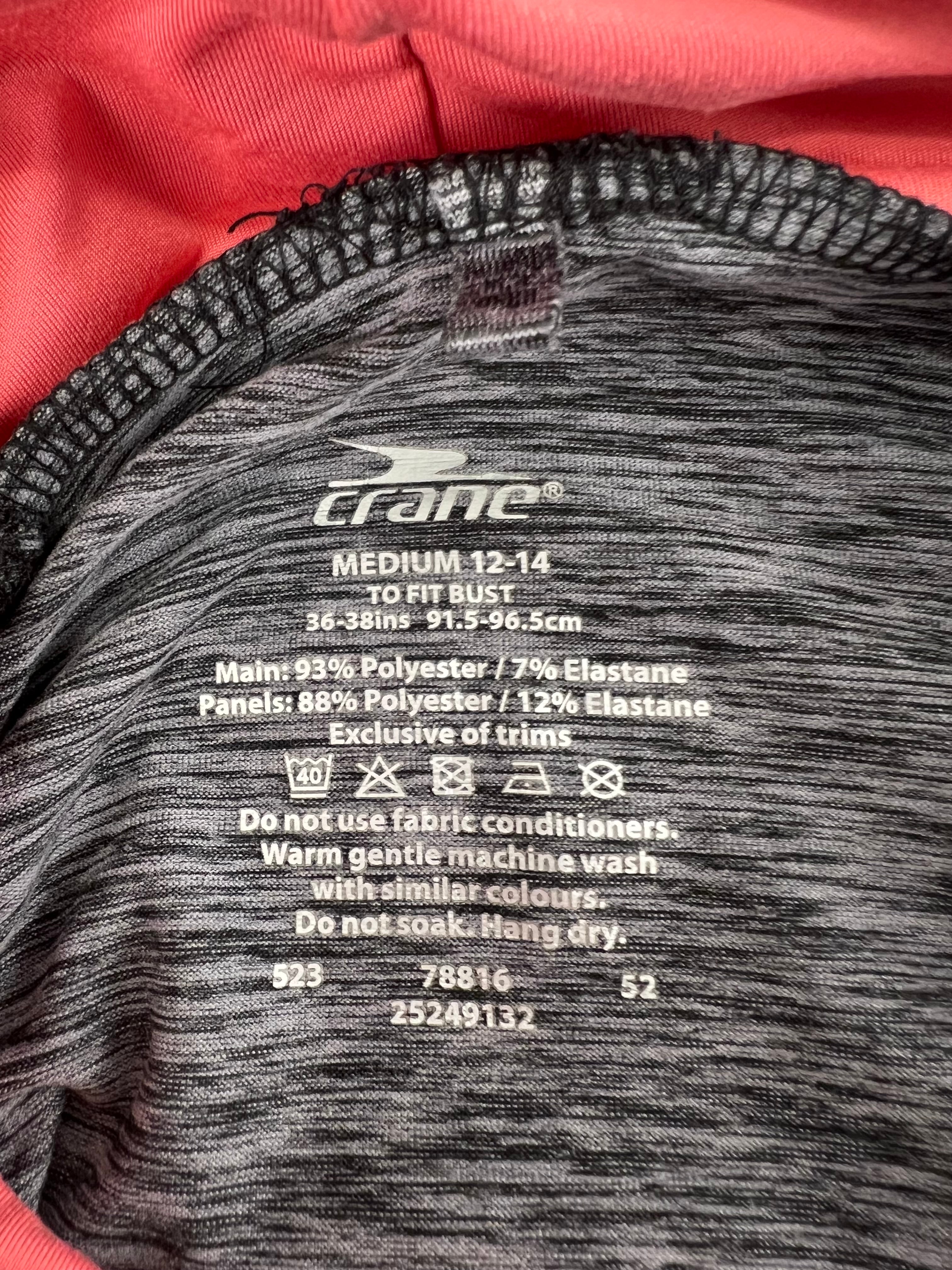 Close-up of Crane top label showing size Medium 12-14 with fabric composition and washing instructions