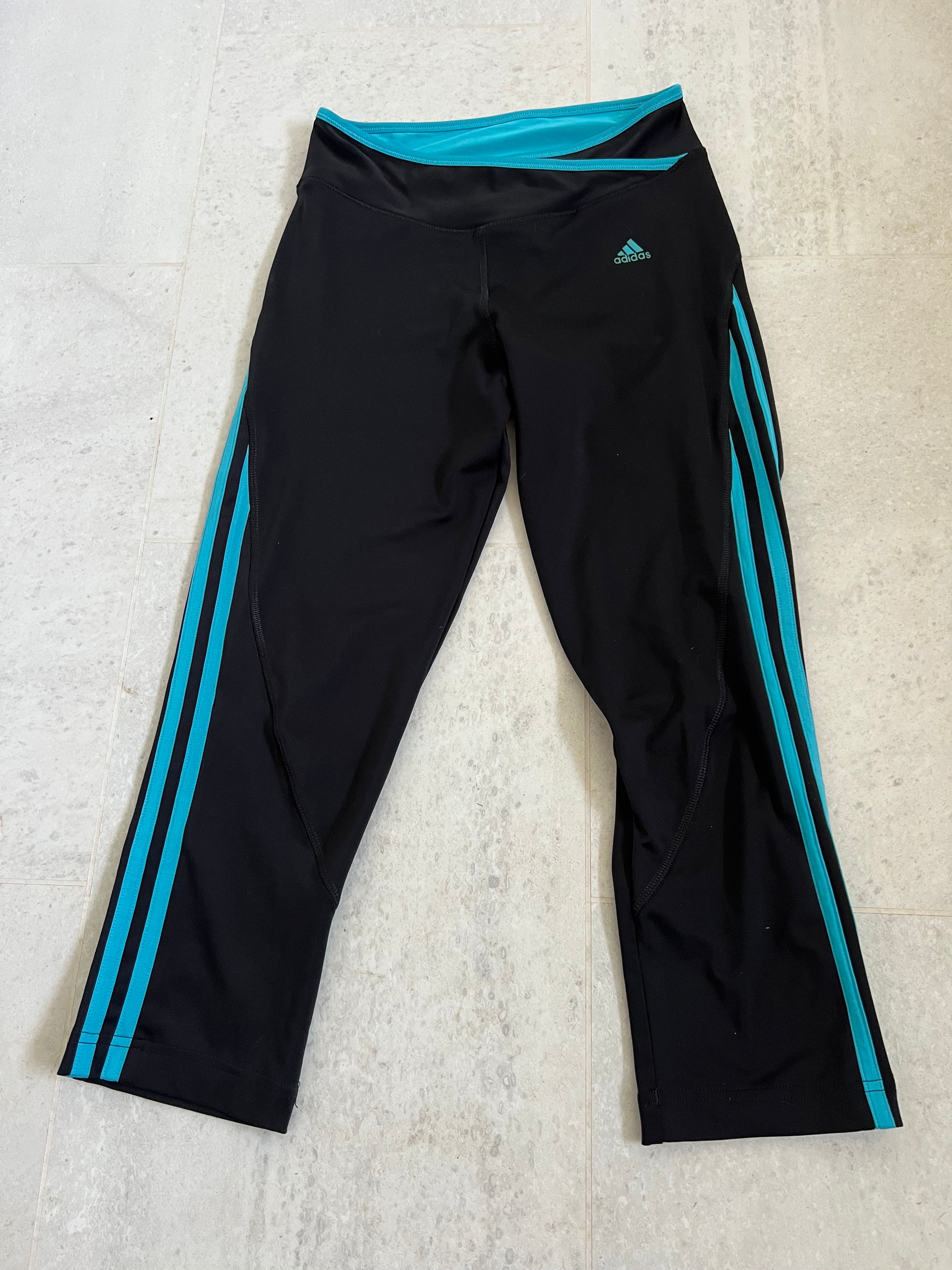 Front view of Adidas black cropped leggings with turquoise side stripes and logo