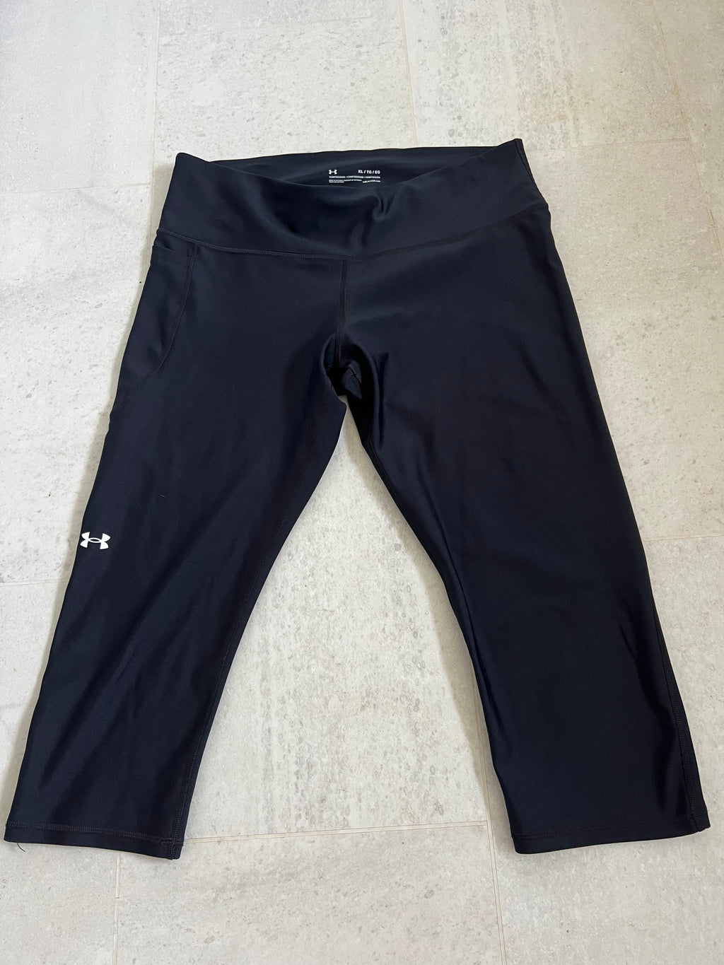 Under Armour black cropped compression leggings laid flat showing front side