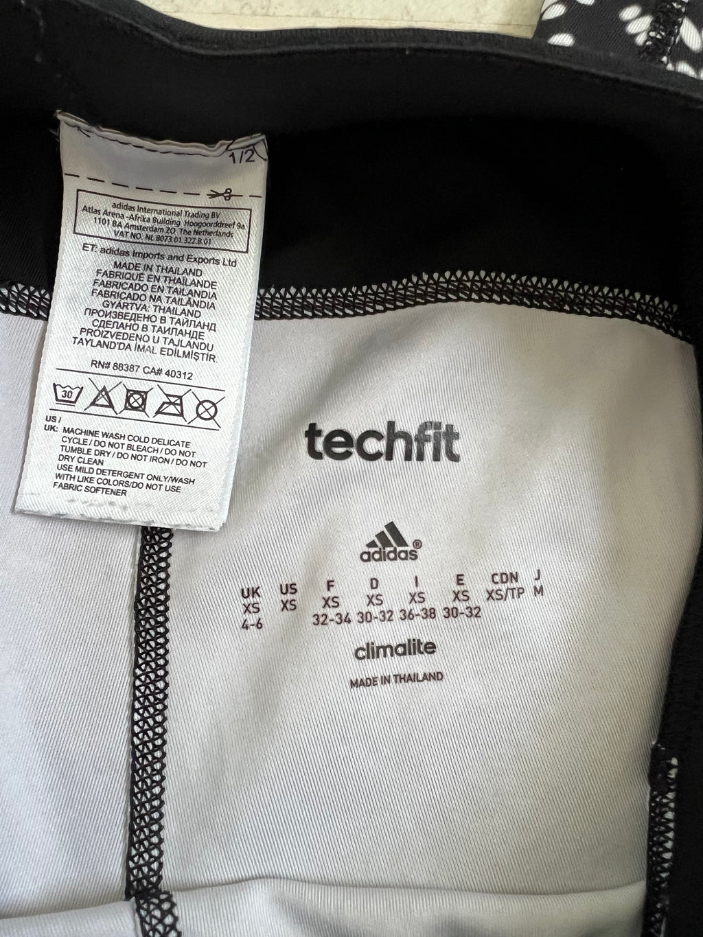 inside label of adidas Techfit black and white pattern leggings showing size XS and care instructions