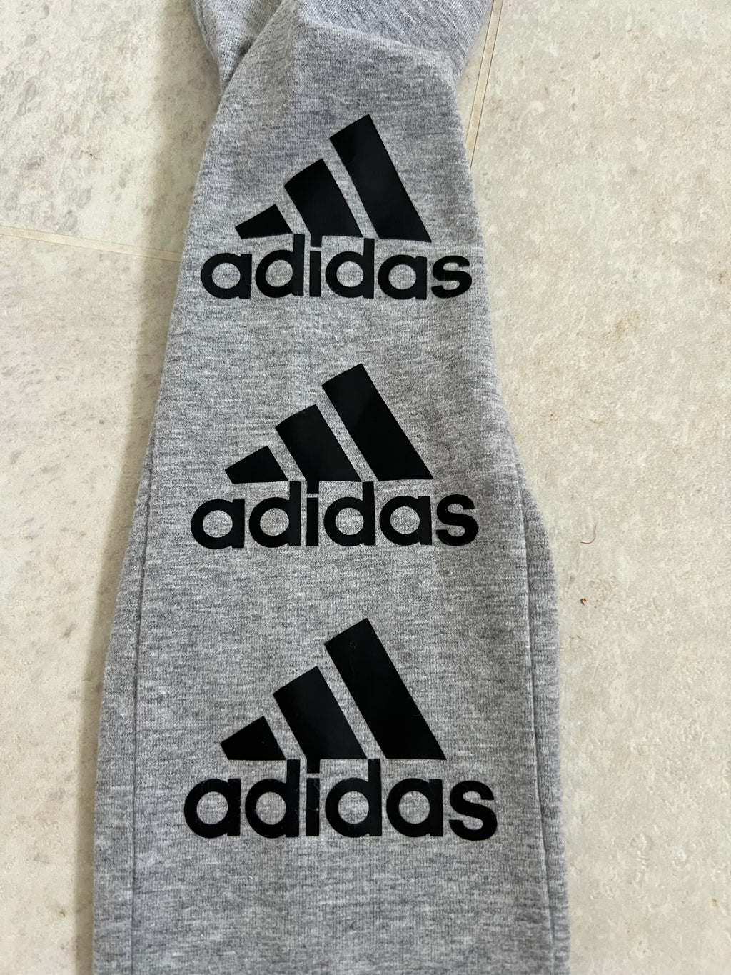 close-up of adidas black logo prints on grey leggings fabric