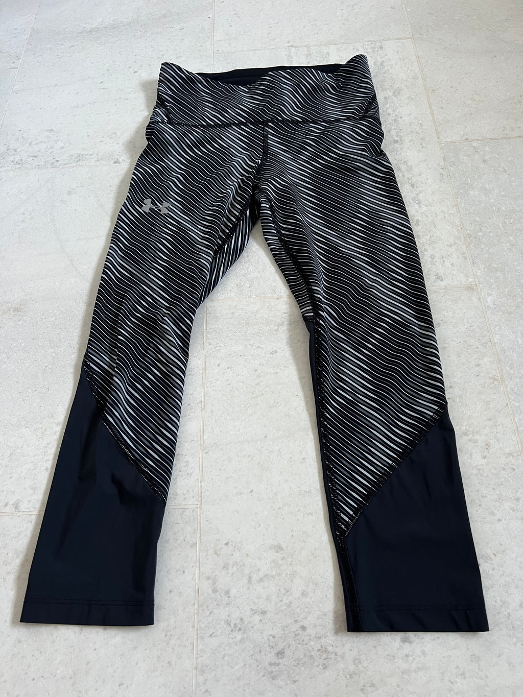 Front view of Under Armour compression cropped leggings featuring grey and black wavy stripe pattern with black lower panels