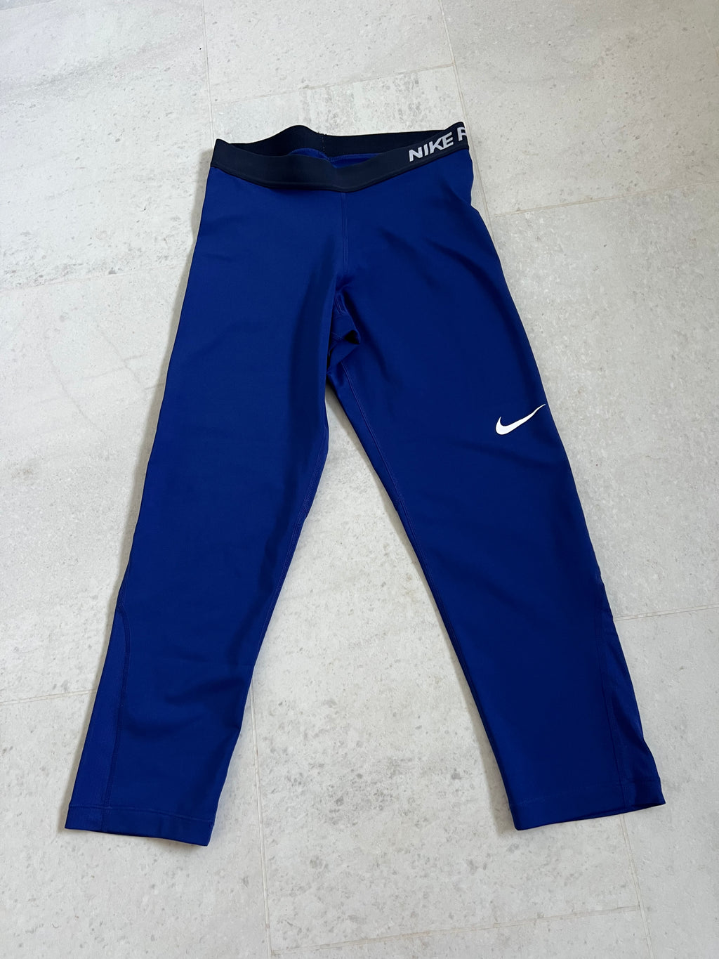 Front view of Nike Pro blue leggings with elasticated black waistband and white Nike logo