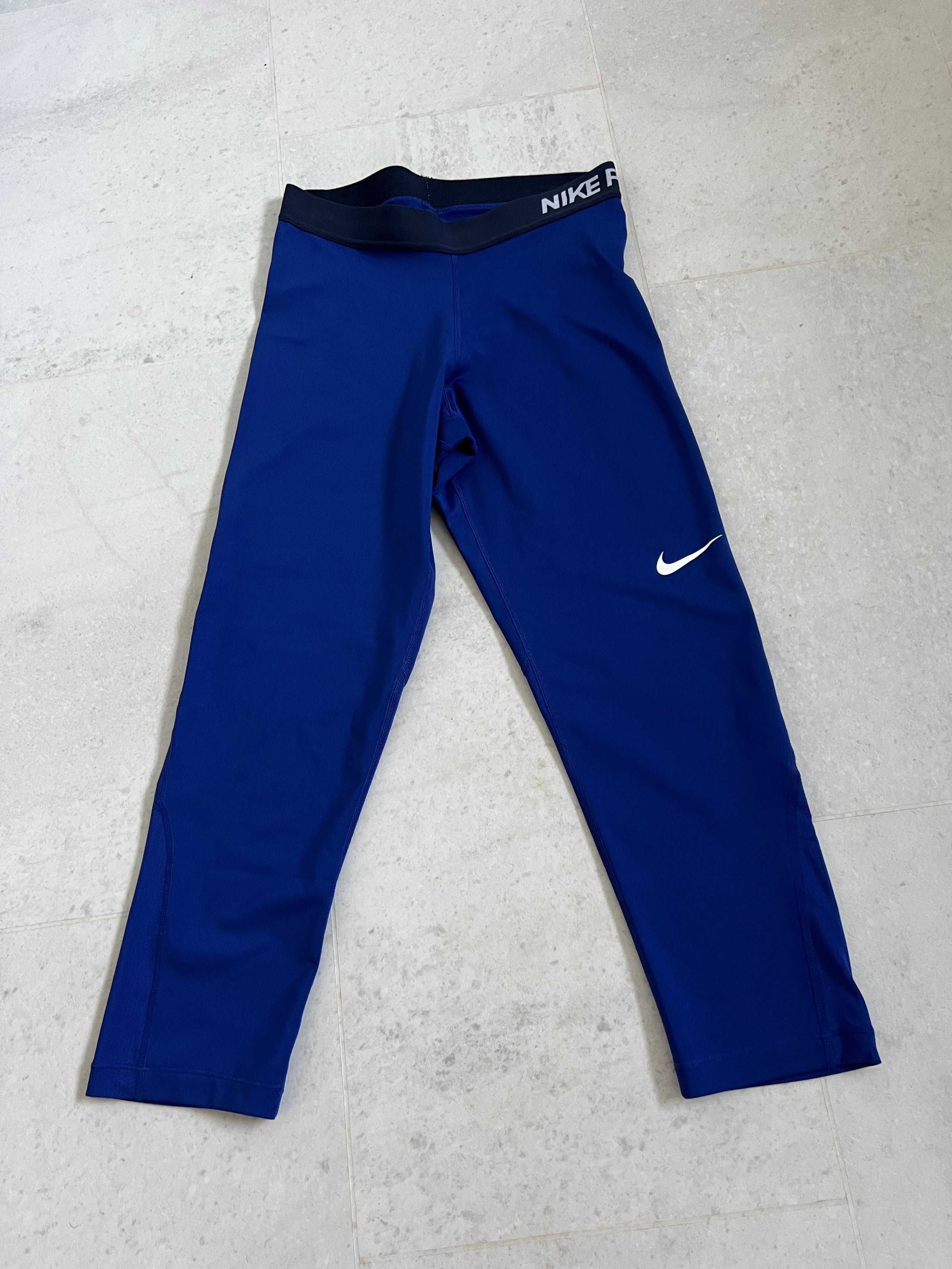 Front view of Nike Pro blue leggings with elasticated black waistband and white Nike logo