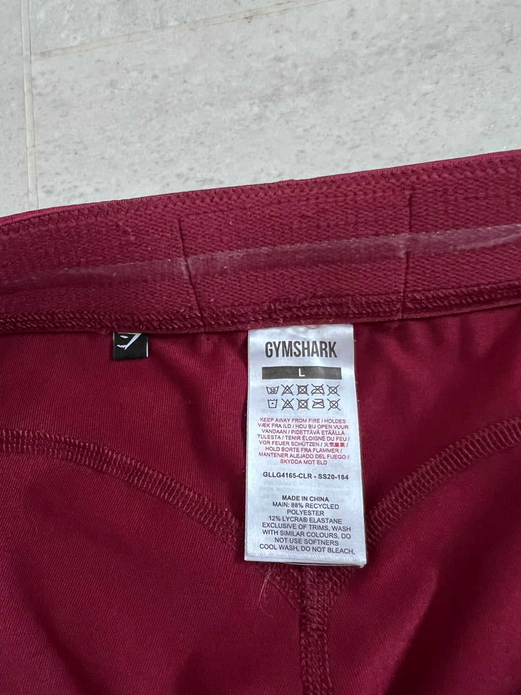 Close-up of size tag inside burgundy Gymshark leggings detailing fabric composition and care instructions