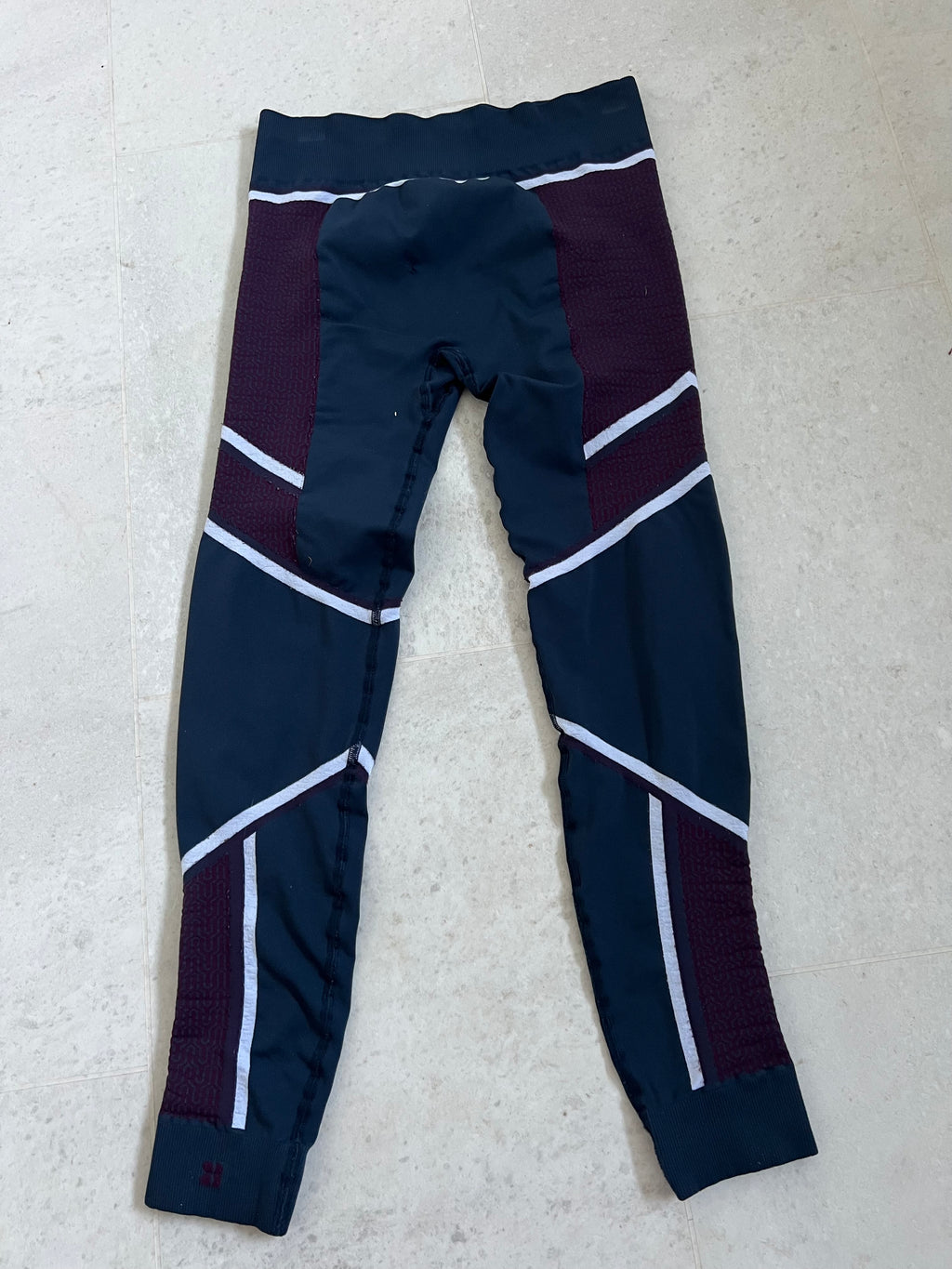 Back view of Sweaty Betty multi-coloured patterned leggings showing the ribbed waistband and ankle cuffs