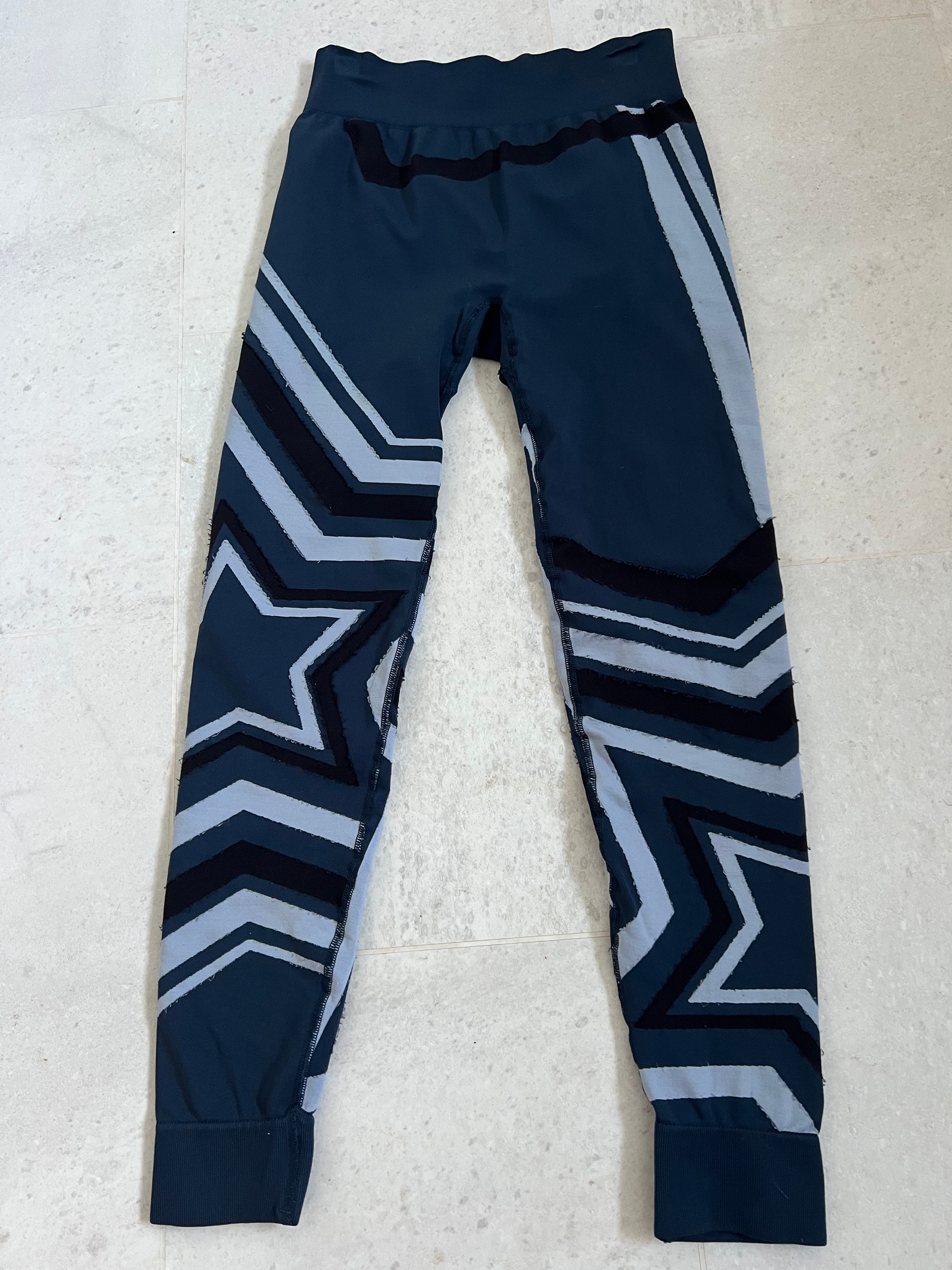 Front view of Sweaty Betty navy leggings with black and grey star and stripe patterns