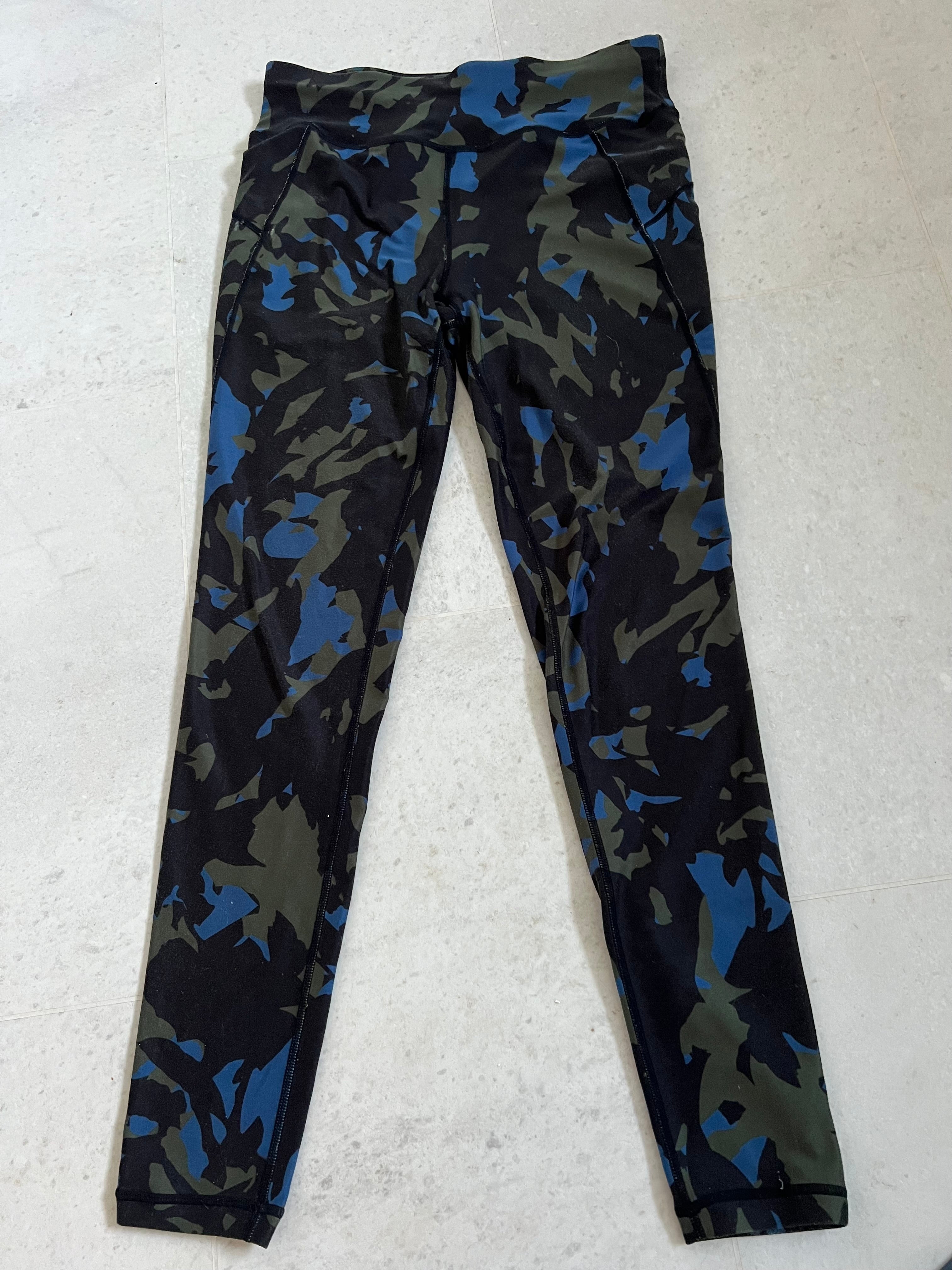 Front view of Sweaty Betty full length leggings in camouflage print with shades of black, green, and blue laid flat