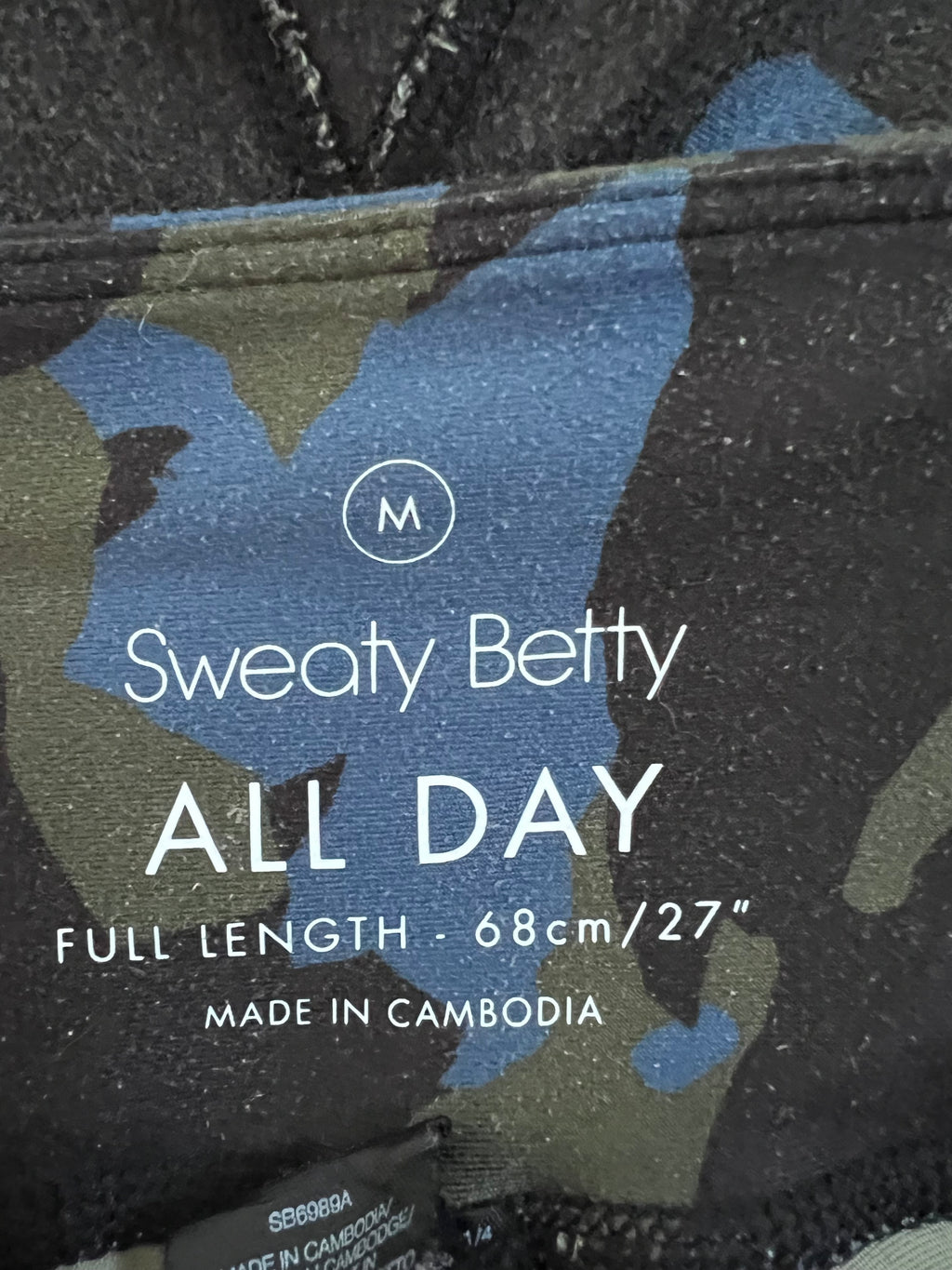 Close-up of size label on Sweaty Betty leggings showing size medium, 'All Day' style, and made in Cambodia