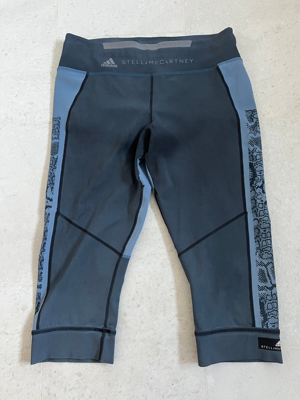 Front view of Adidas x Stella McCartney blue cropped leggings with snakeskin side pattern and branded waistband