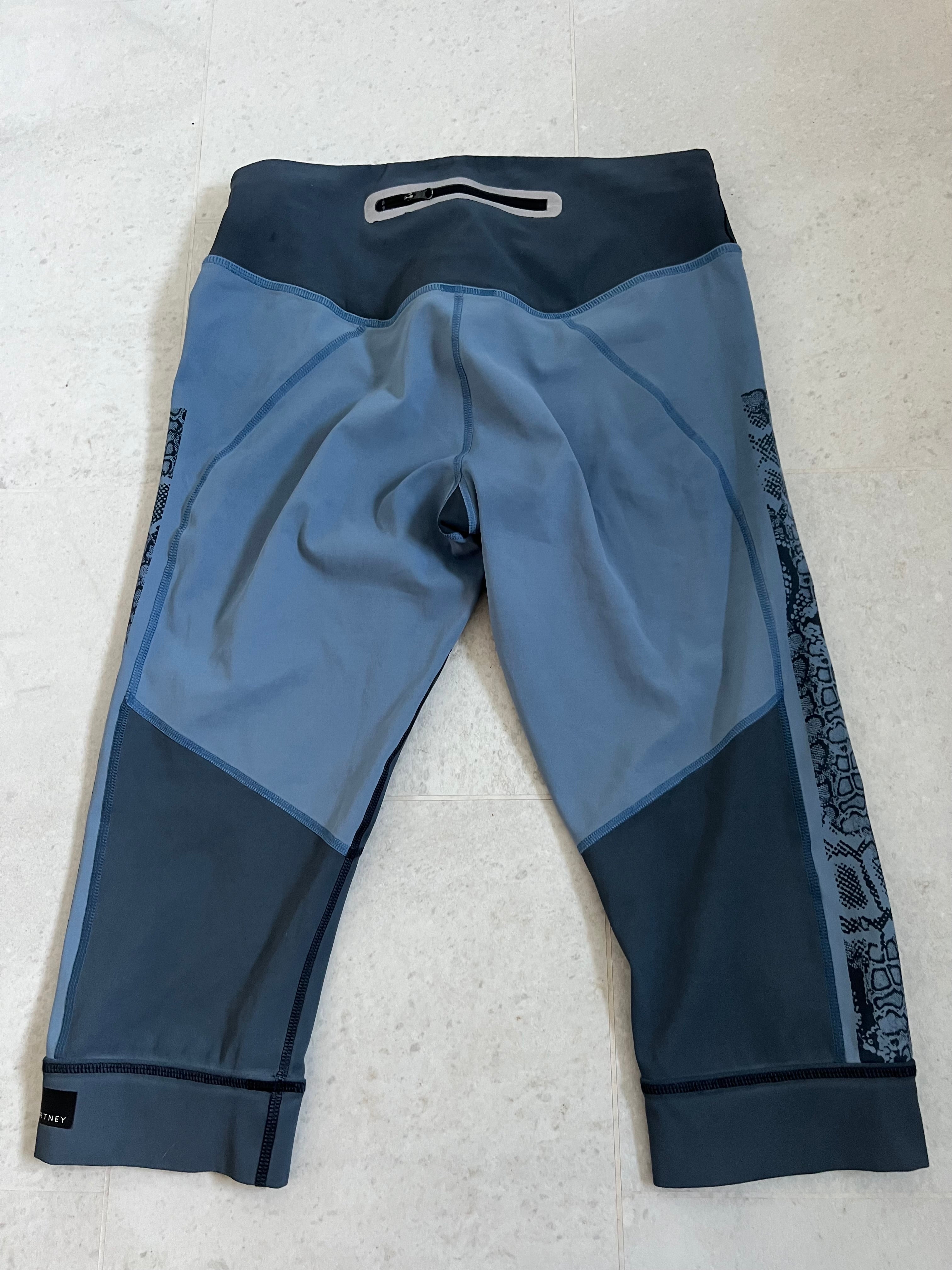Back view of Adidas x Stella McCartney blue cropped leggings showing zip pocket and contrasting fabric panels
