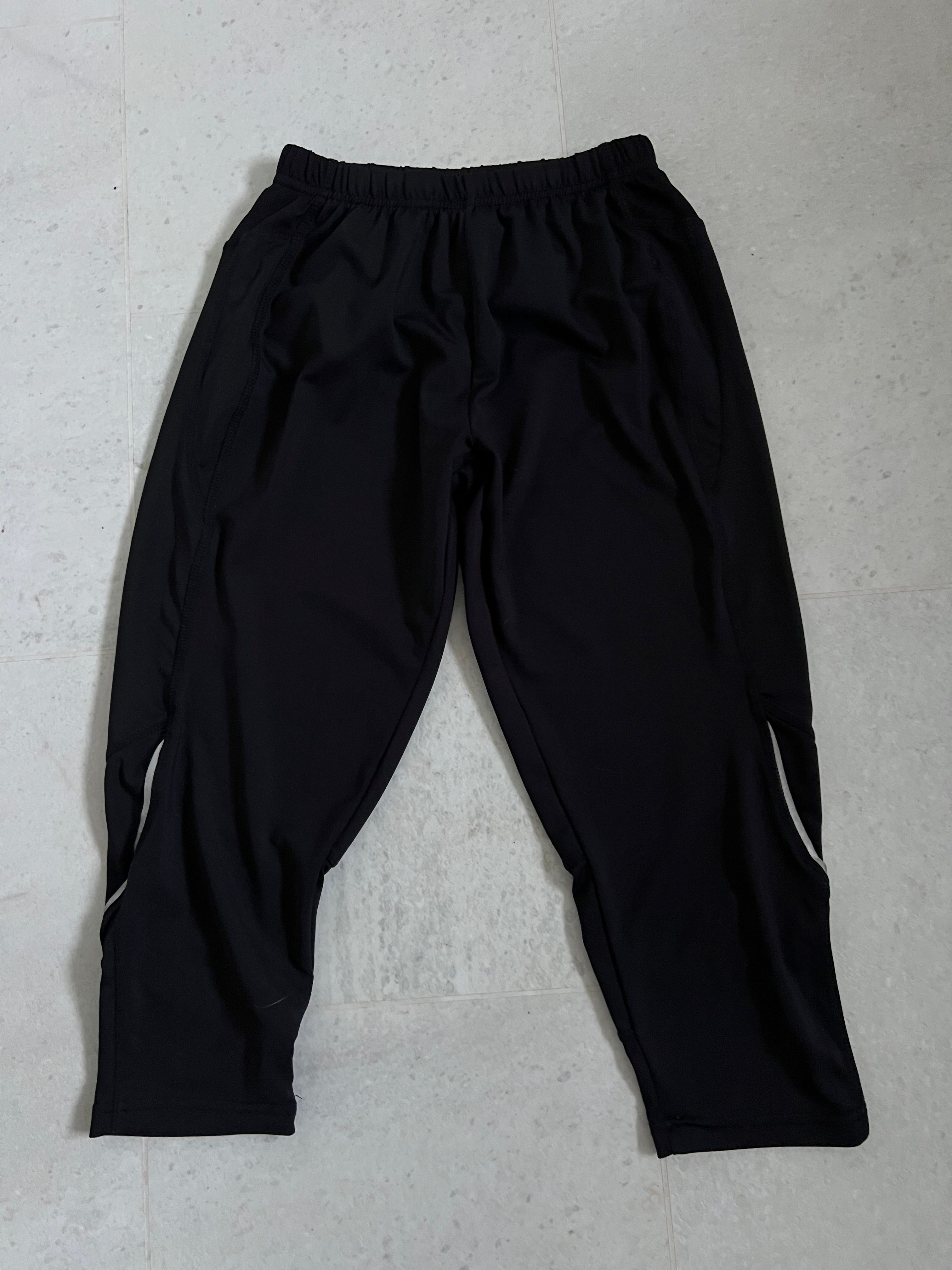 Front view of Karrimor black cropped leggings with elastic waistband laid flat on a light tile floor