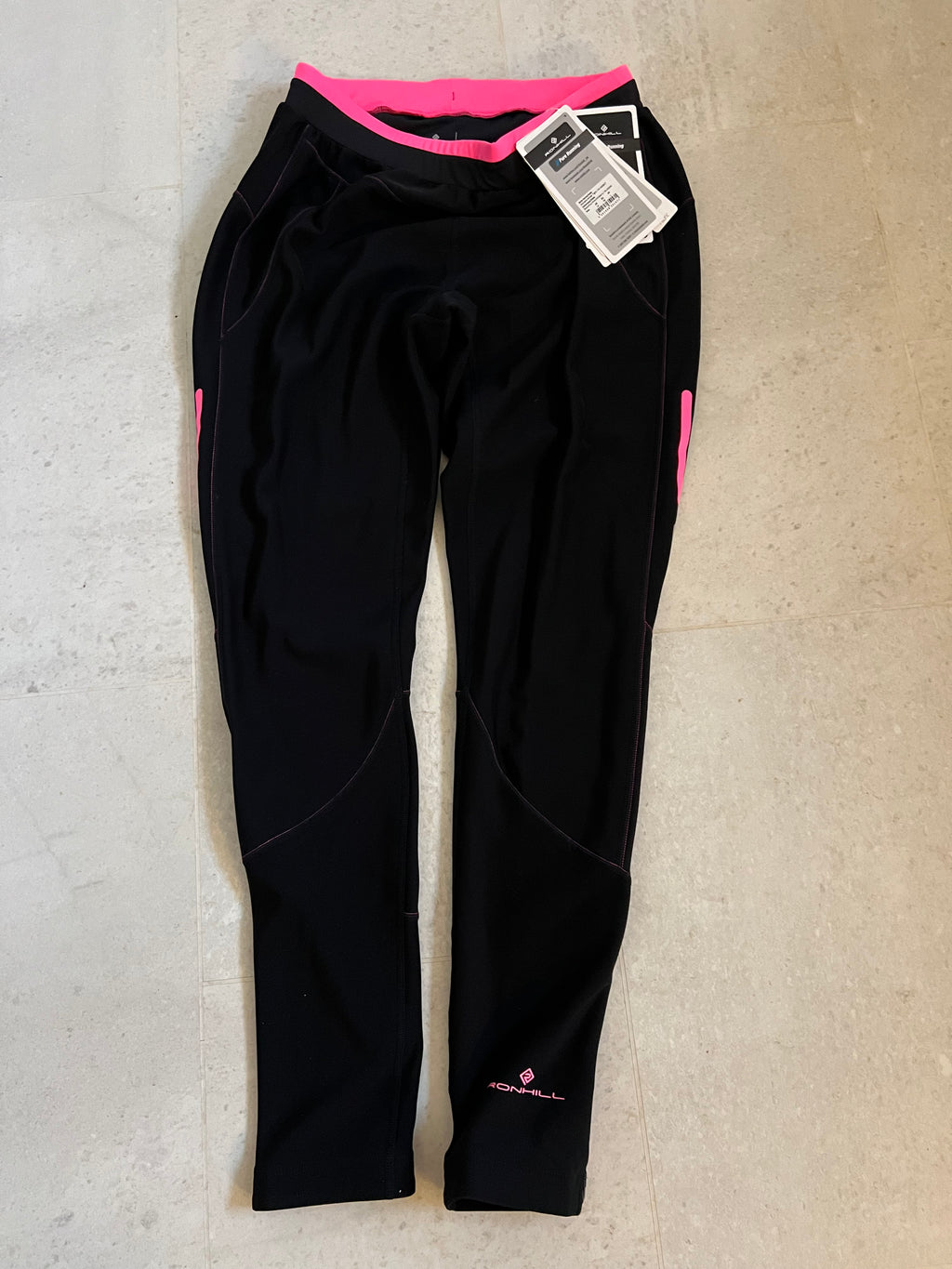 Ronhill black full length women's winter running leggings with pink accents and tags laid flat