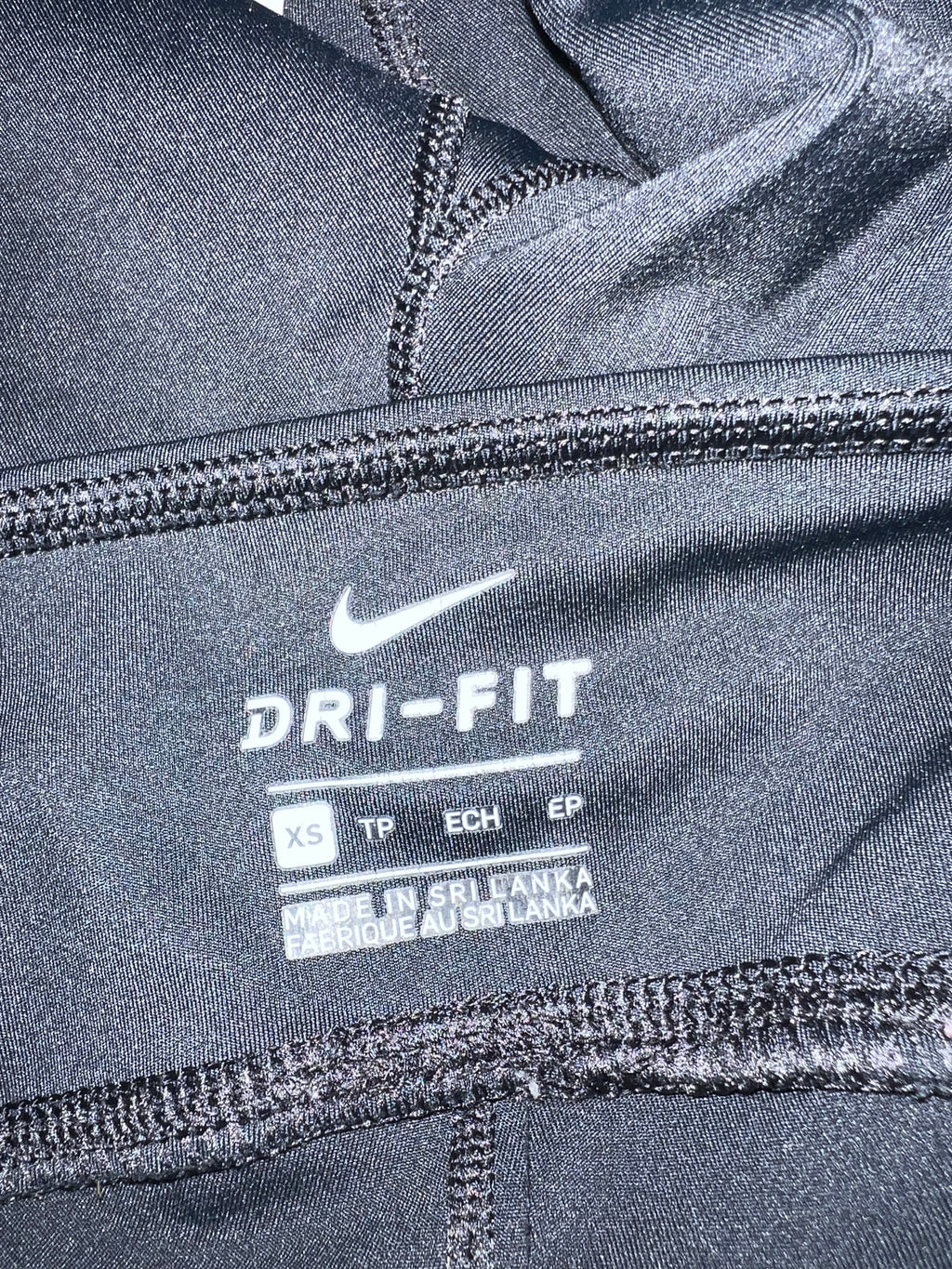 Close-up of the inner label showing Nike Dri-Fit branding and size XS in black cropped leggings