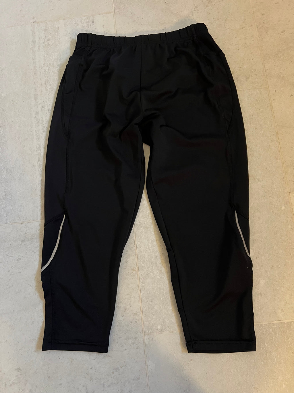 Front view of black Karrimor cropped leggings with elastic waistband and reflective detailing on legs