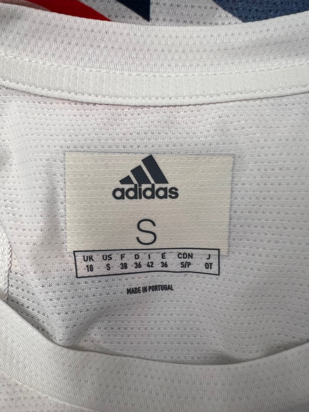 Close-up of Adidas size label inside white vest top made in Portugal