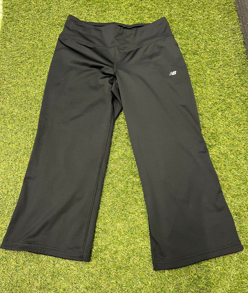 Front view of black New Balance Lightning Dry cropped leggings laid flat on grass