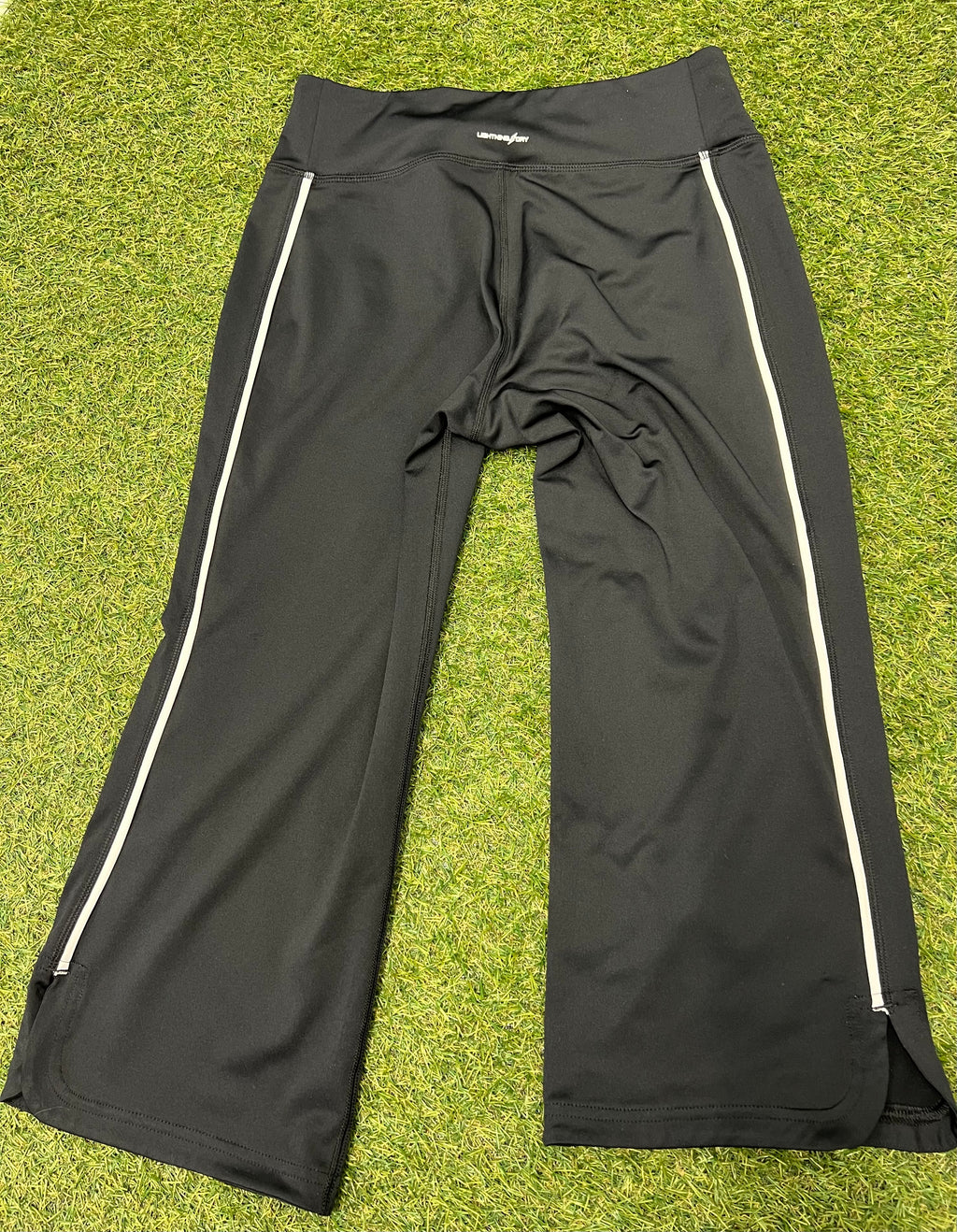 Rear view of black New Balance Lightning Dry cropped leggings showing reflective side stripes