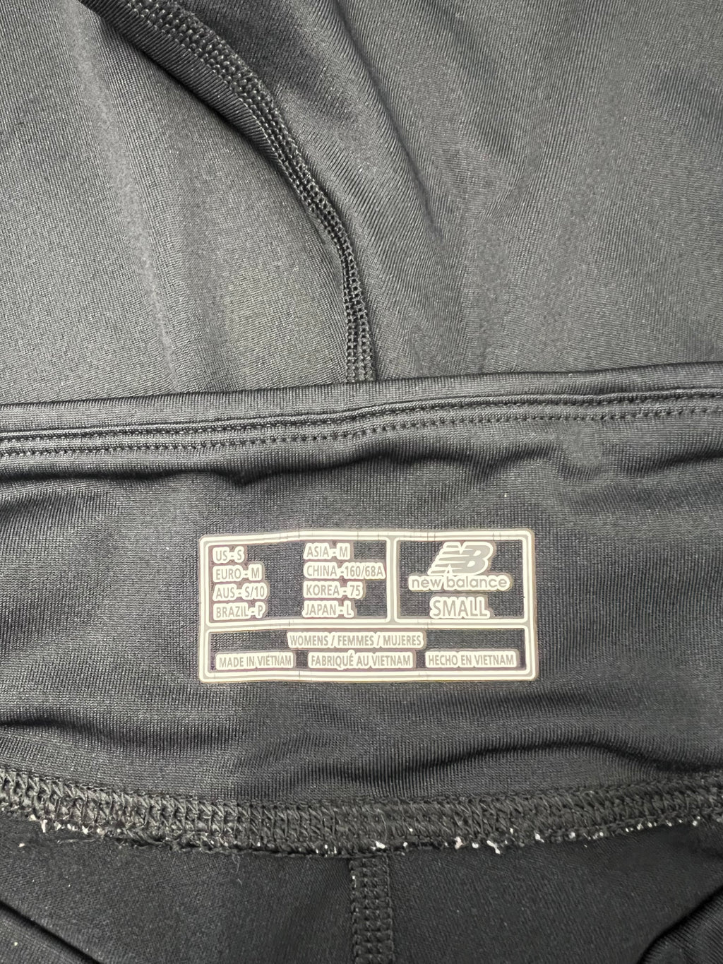 Inside label of New Balance Lightning Dry cropped leggings showing size and manufacturing details