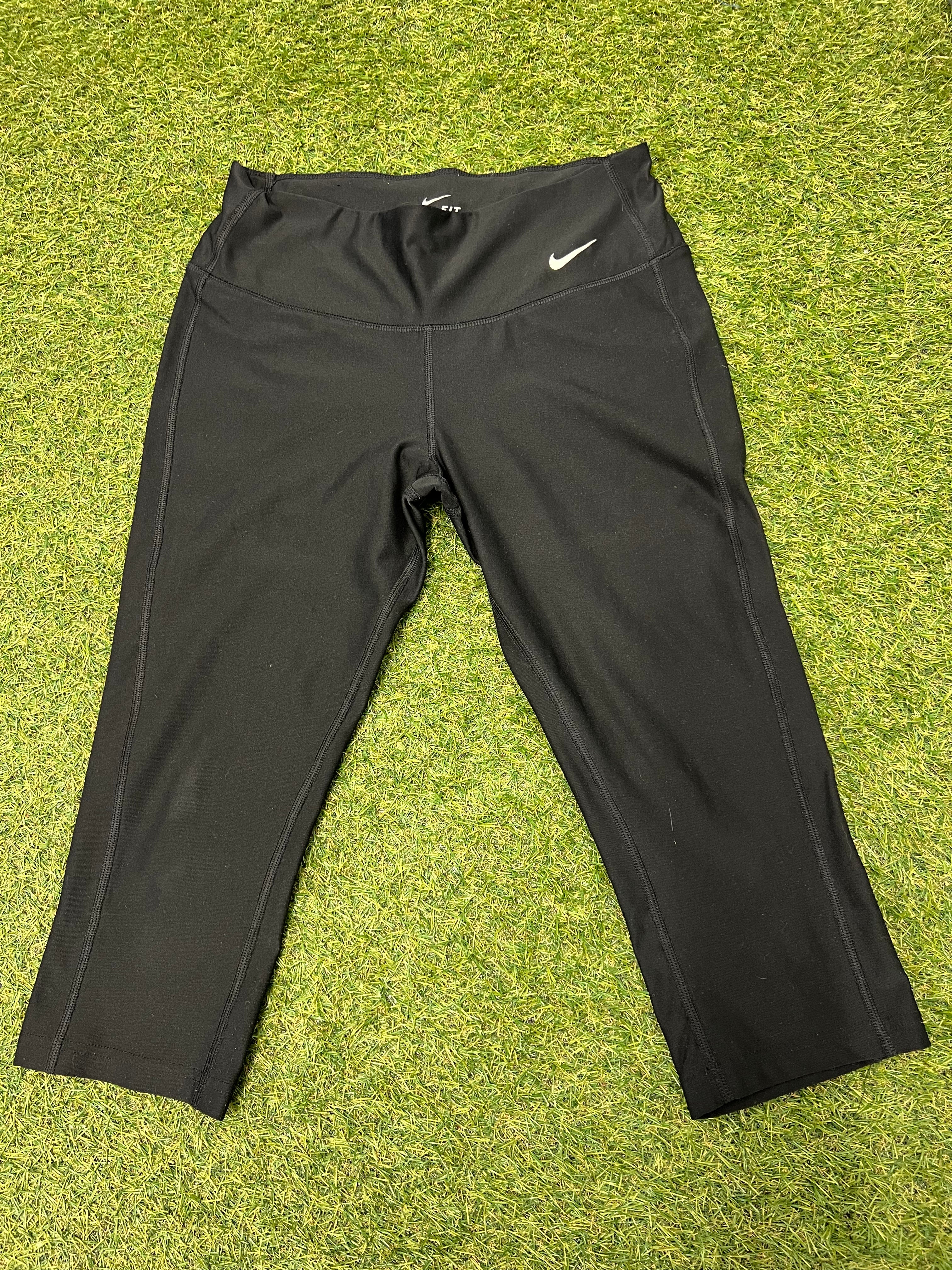 Front view of Nike Dri-FIT black cropped leggings laid flat on grass